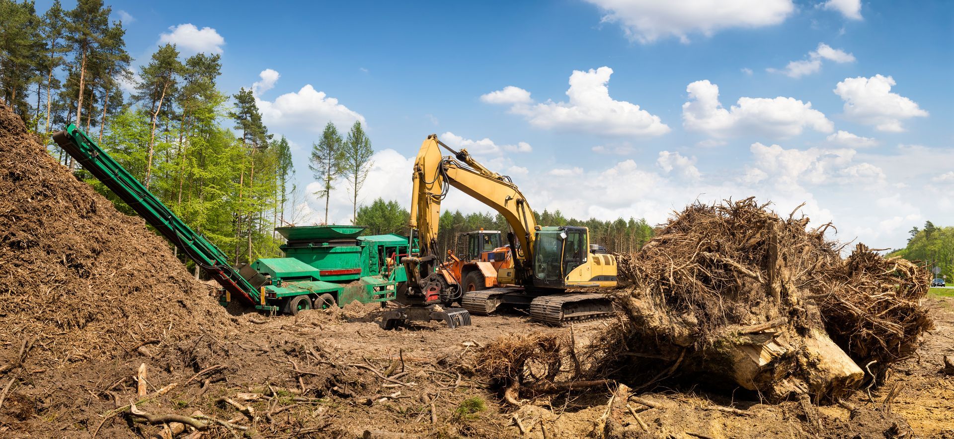 A large pile of dirt is being processed by a machine in a field.