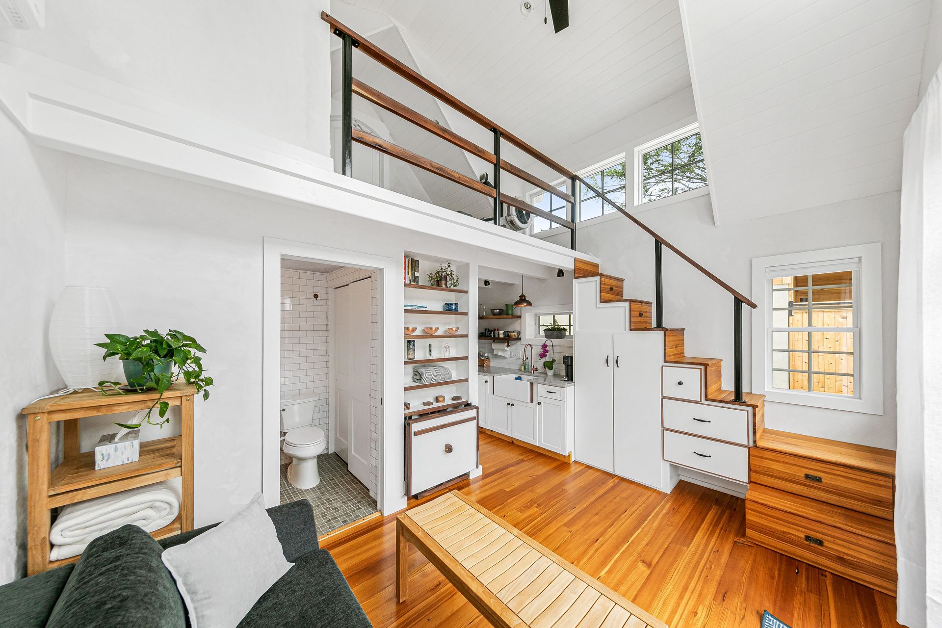 A living room with a couch , table , and stairs leading to a loft.