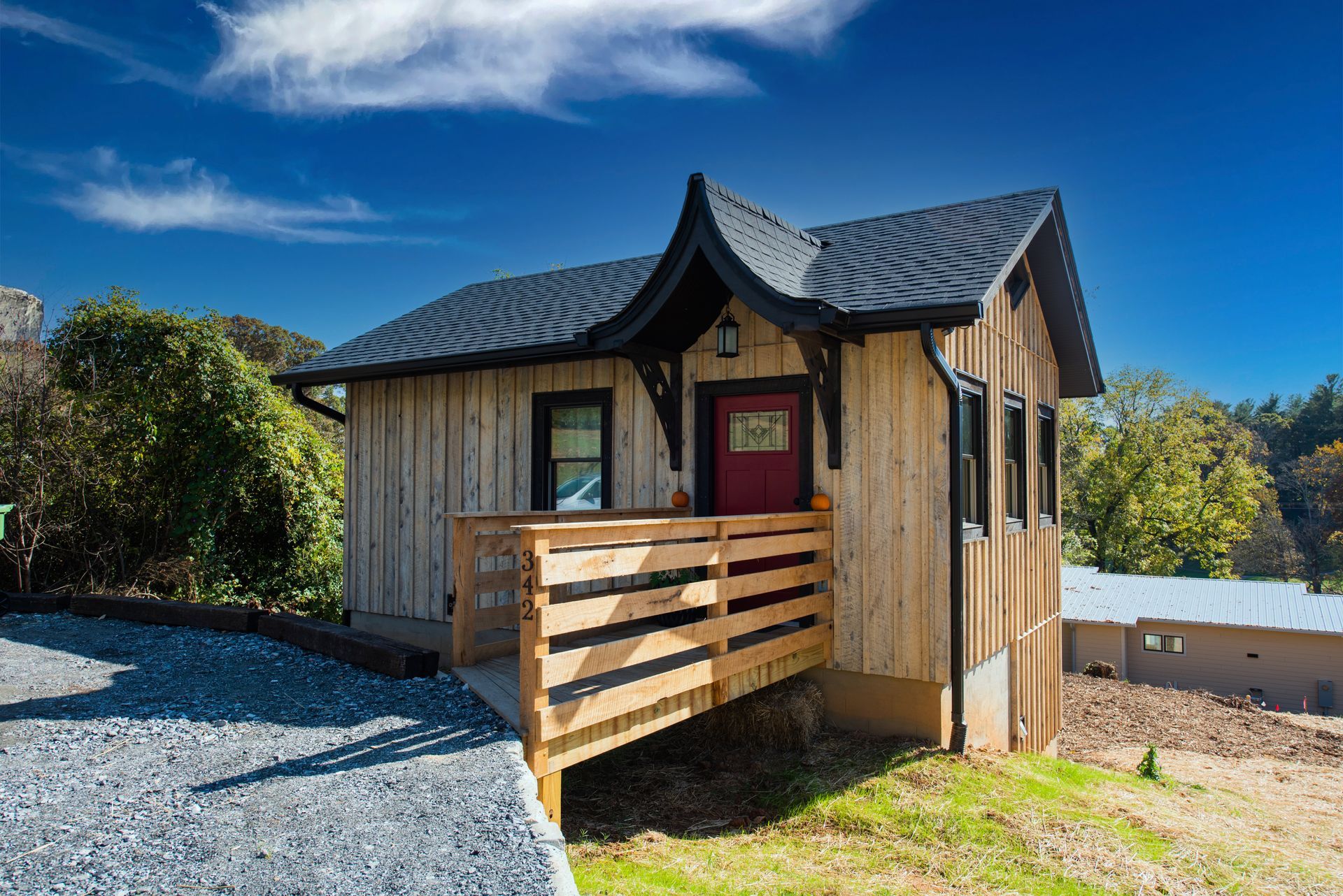 Off-grid tiny cabin in Marshall, NC, built by Nanostead featuring vertical wood siding, black trim, 