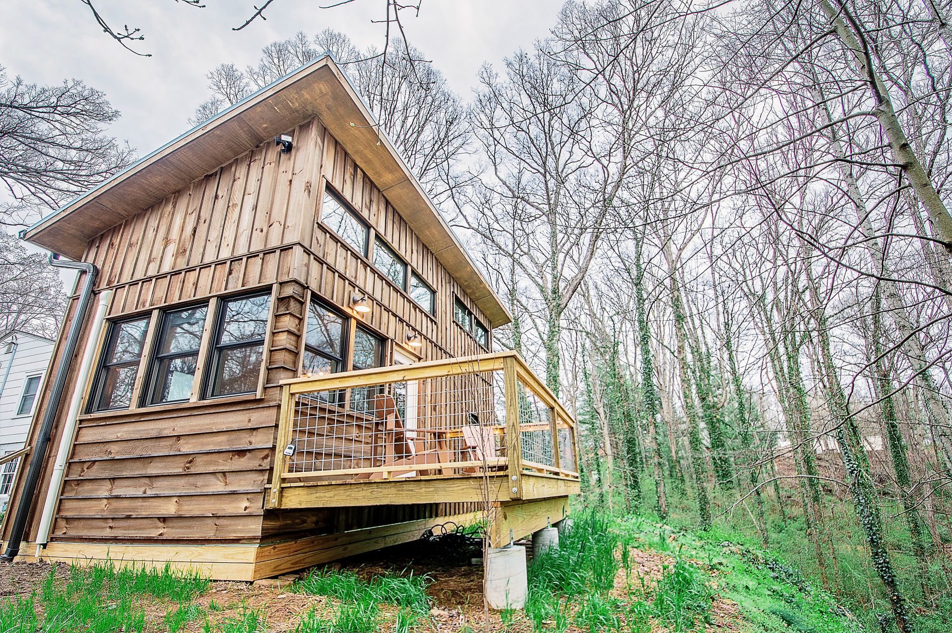 A small wooden house with a deck in the middle of a forest.