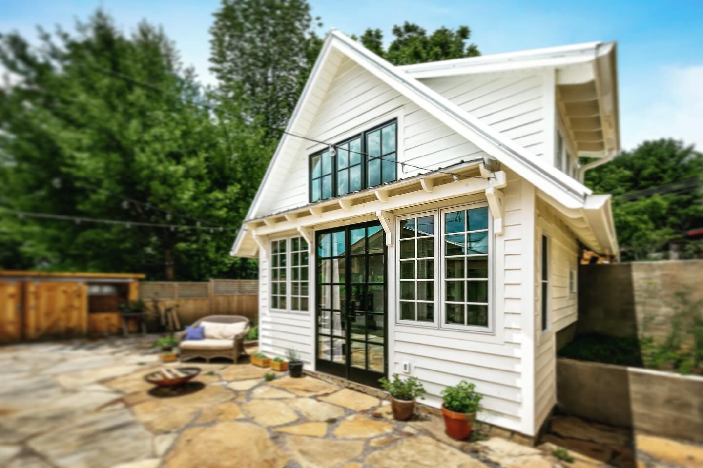 A white house with a lot of windows and a patio in front of it.