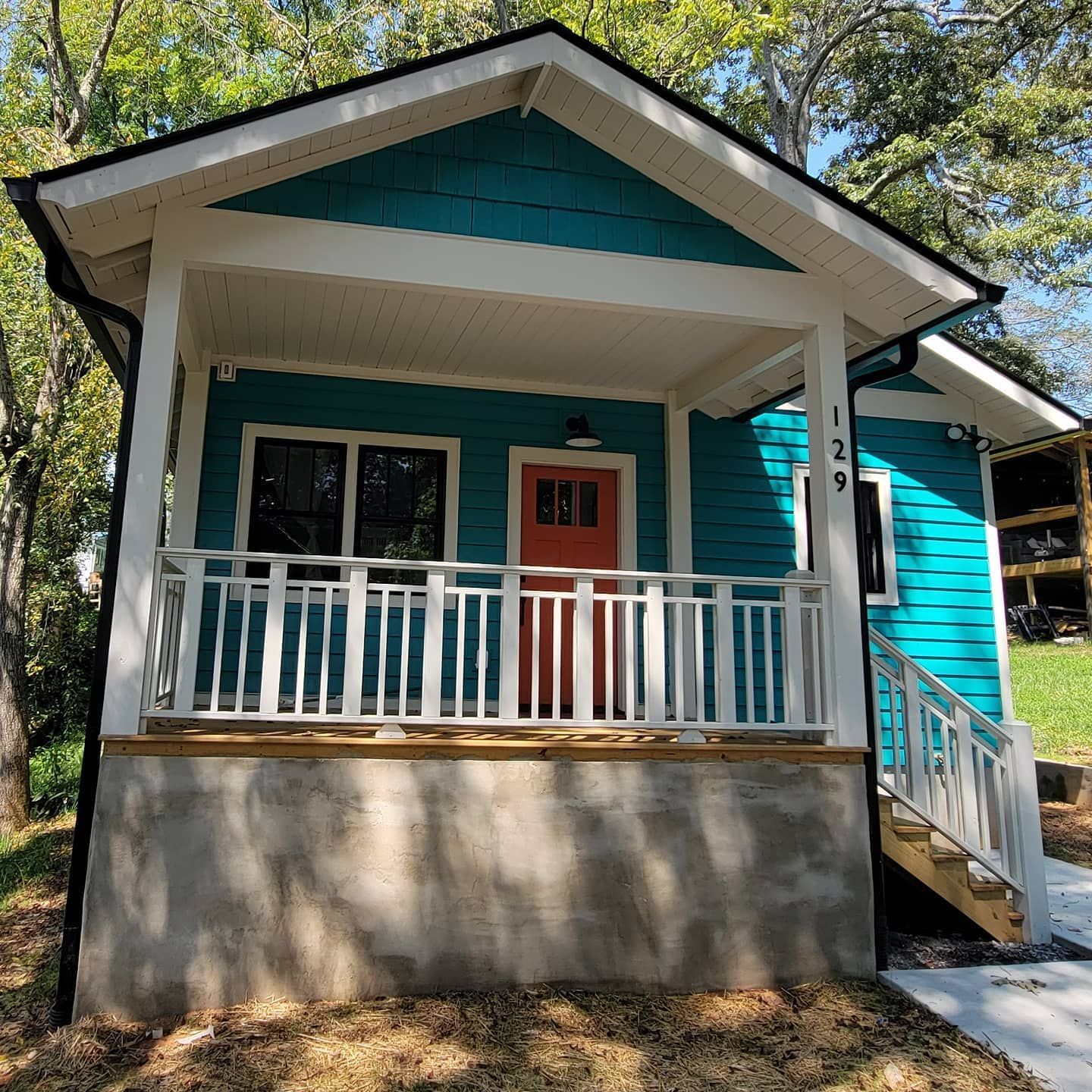 A small blue house with a porch and stairs.