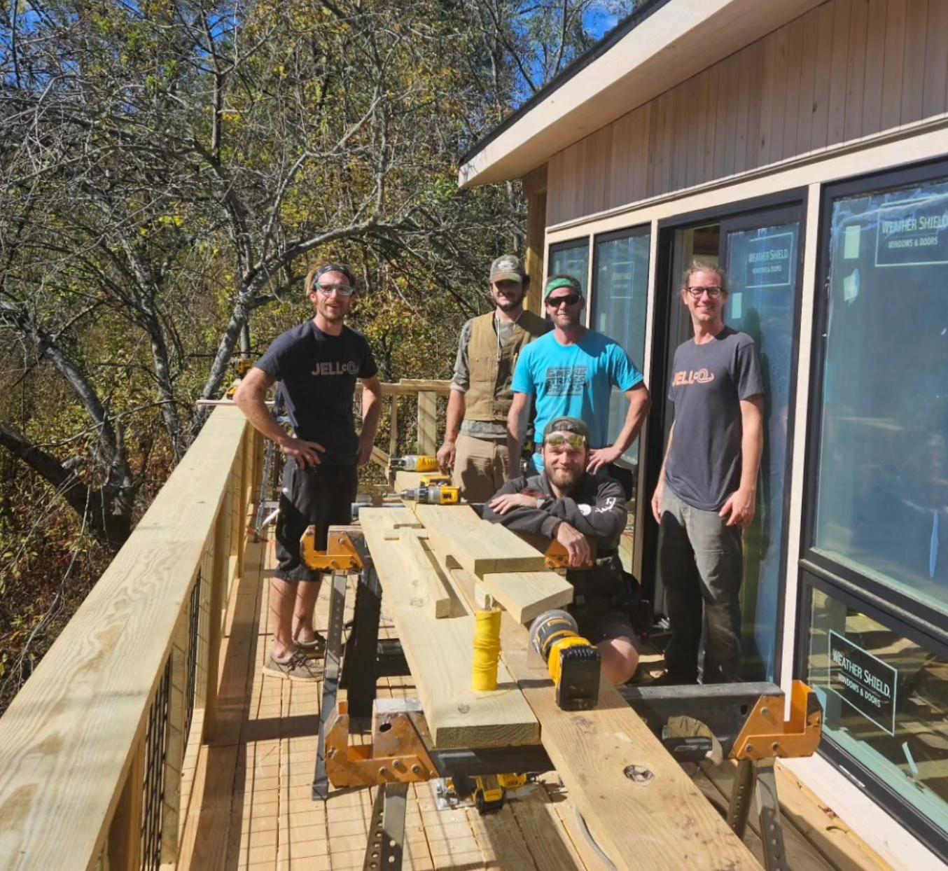 A group of men are posing for a picture on a wooden deck