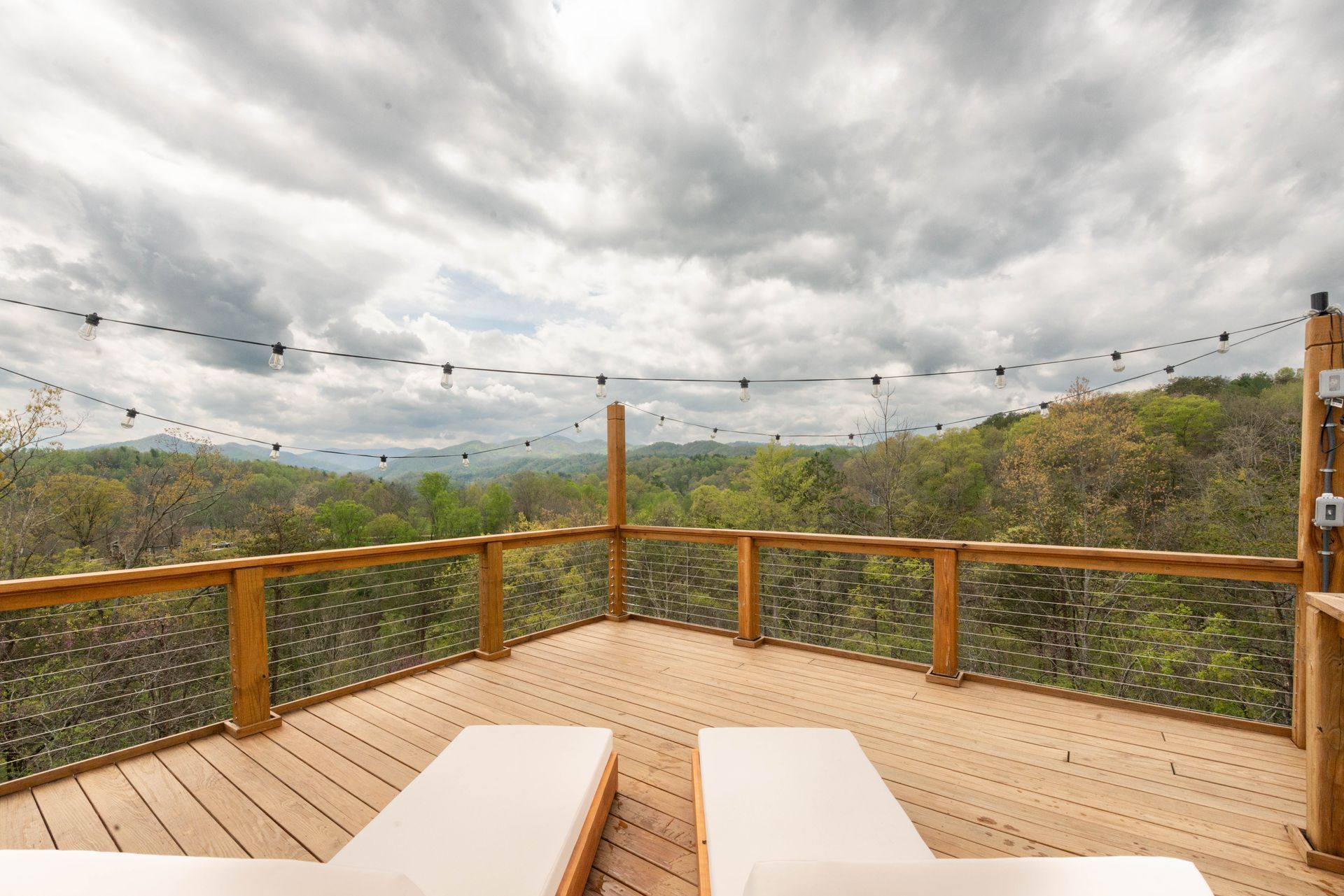 There are two lounge chairs on the deck with a view of the mountains.