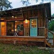 A small wooden house with a blue door and a porch.