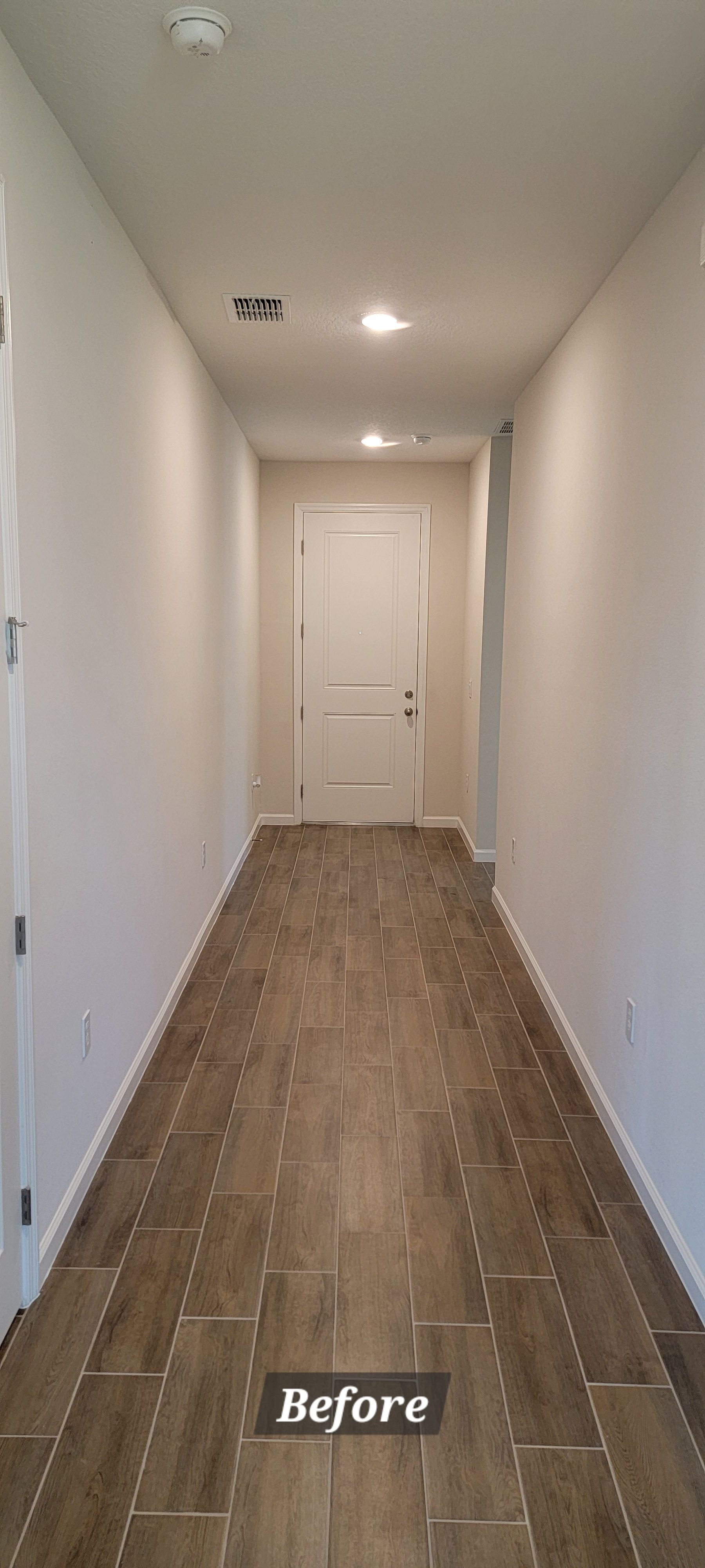 A long hallway with tile floors and white walls.