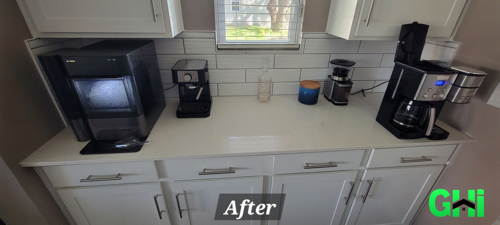 A kitchen with white cabinets and black coffee makers on the counter.
