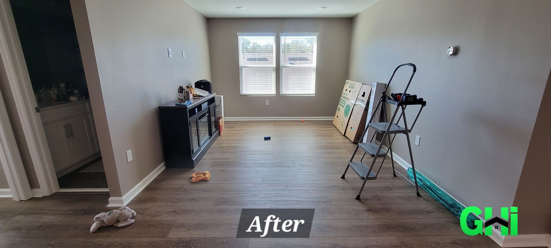 A living room with hardwood floors and a ladder in it.