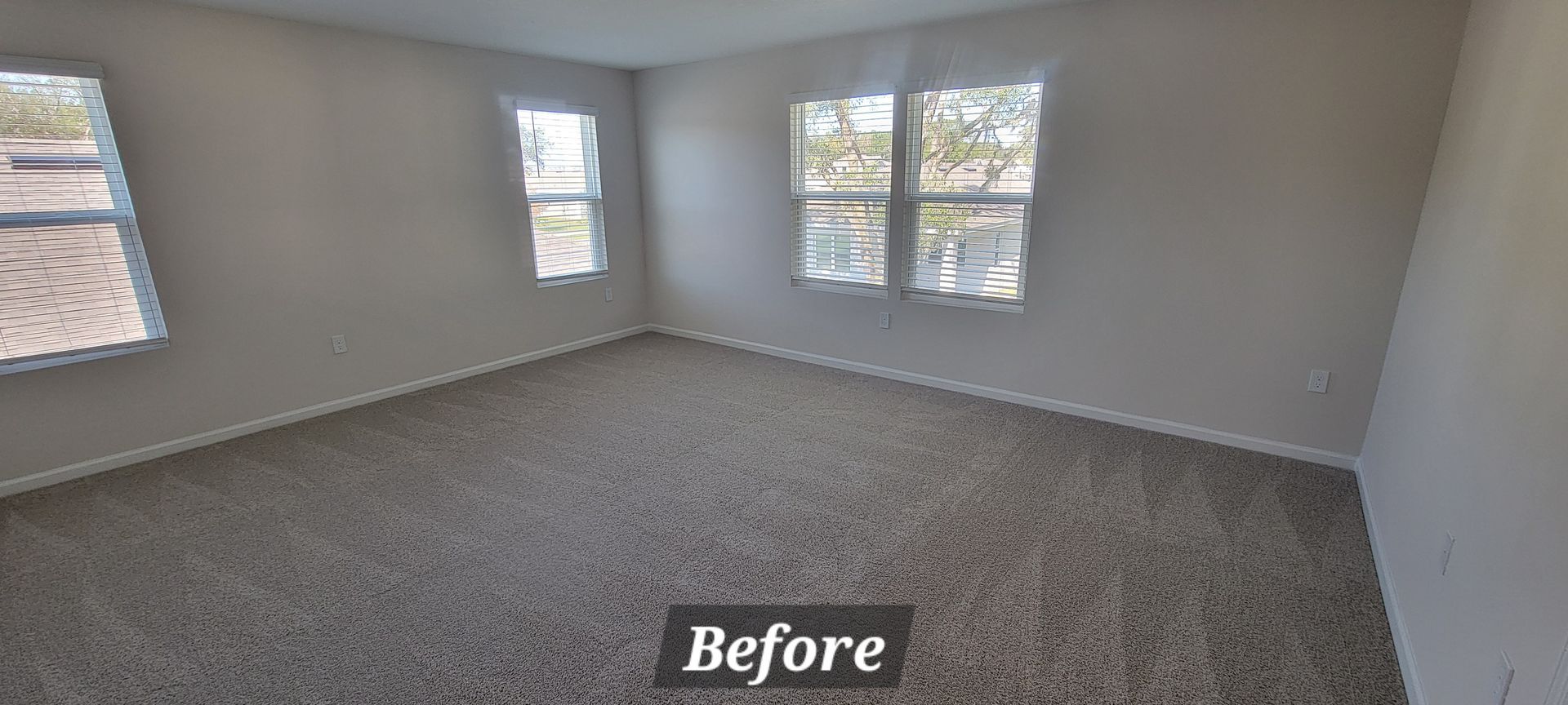A before picture of a bedroom with carpet and windows.