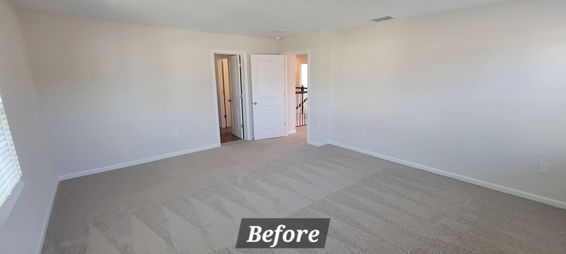 A large empty room with a carpeted floor and white walls.