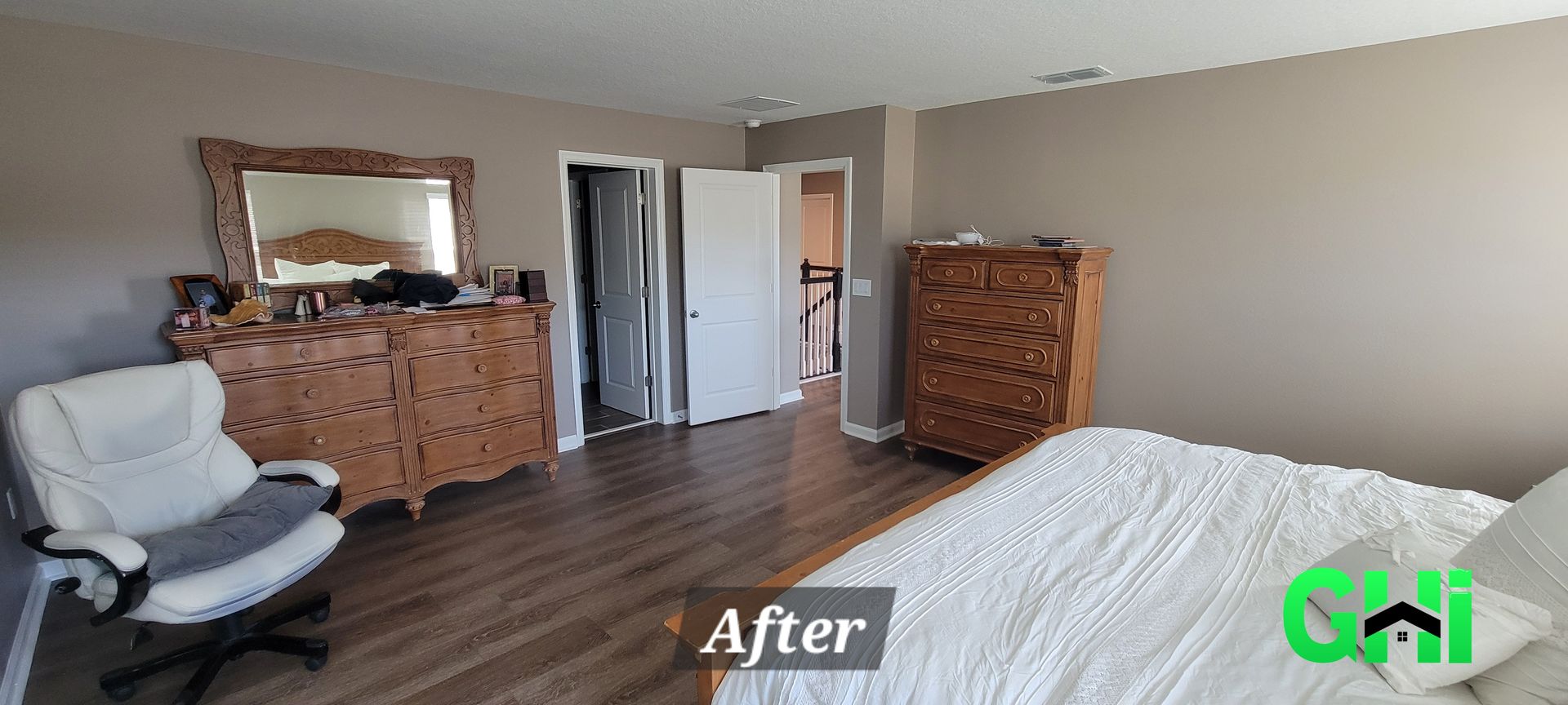 A bedroom with a bed , dresser , chair and mirror.