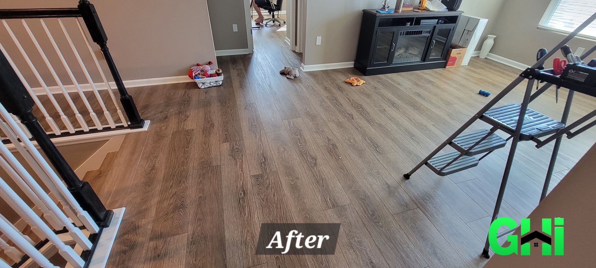 A living room with a wooden floor and stairs.