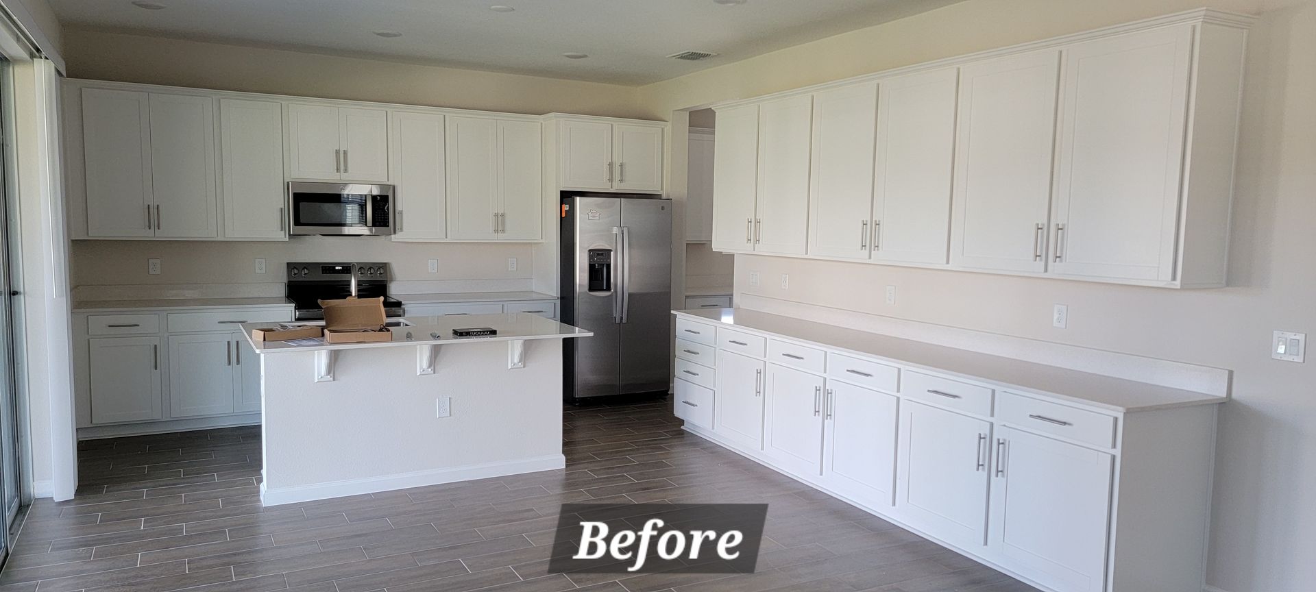 A kitchen with white cabinets and stainless steel appliances before being painted.