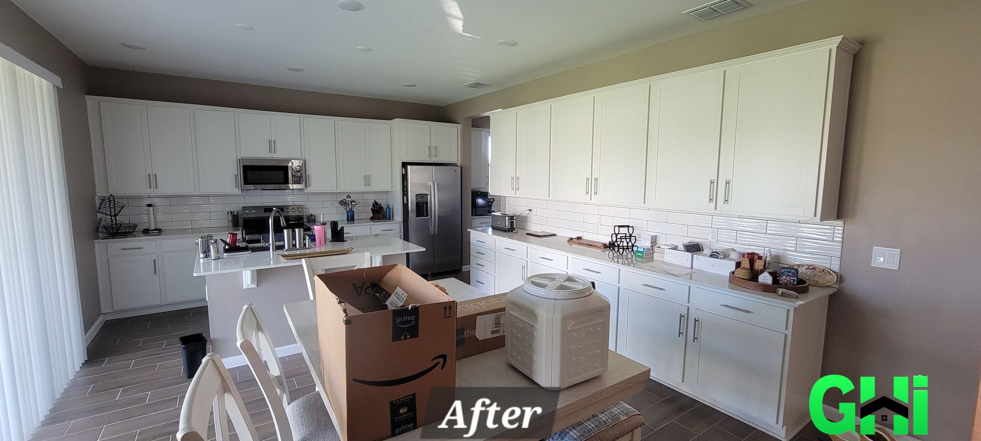 A kitchen with white cabinets , a refrigerator , a microwave , and a stove.