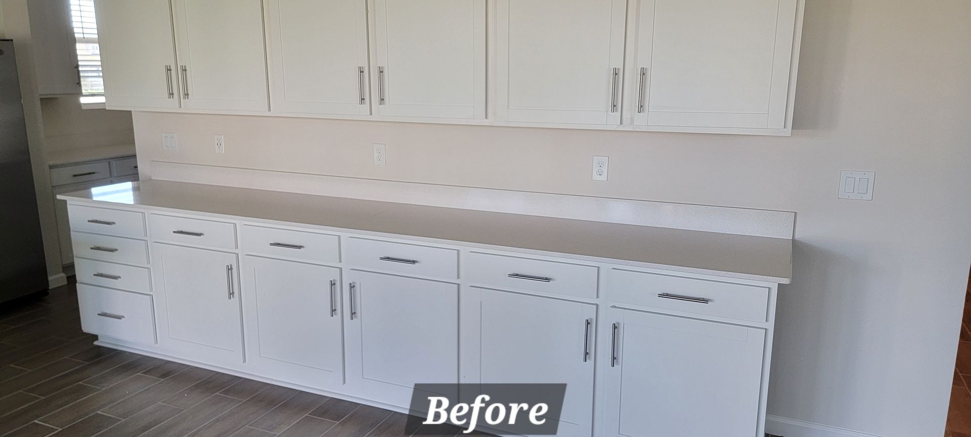 A before picture of a kitchen with white cabinets and counter tops.