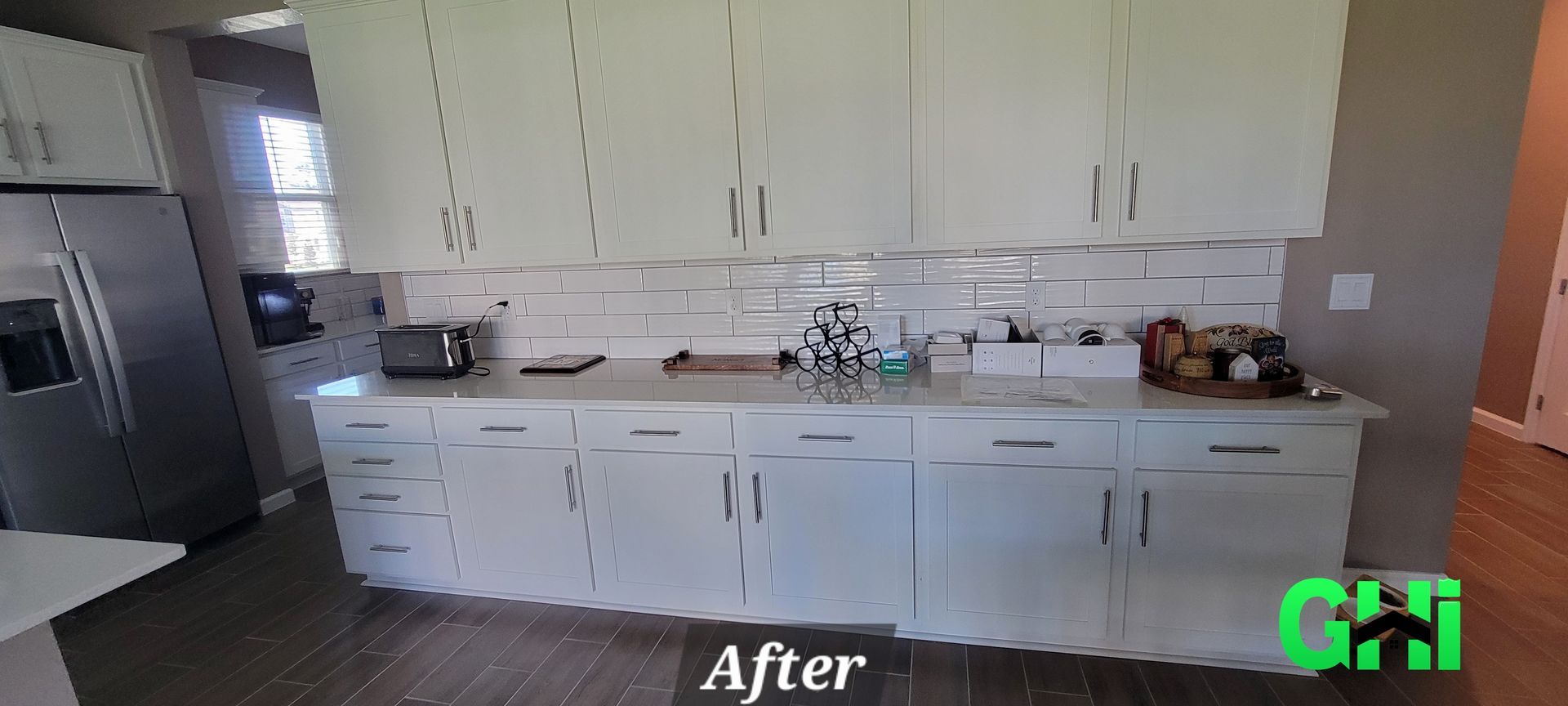 A kitchen with white cabinets and a stainless steel refrigerator.