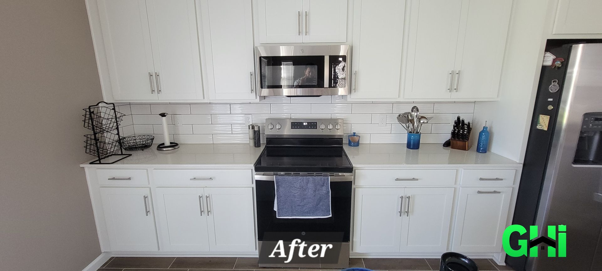 A kitchen with white cabinets , stainless steel appliances , and a refrigerator.