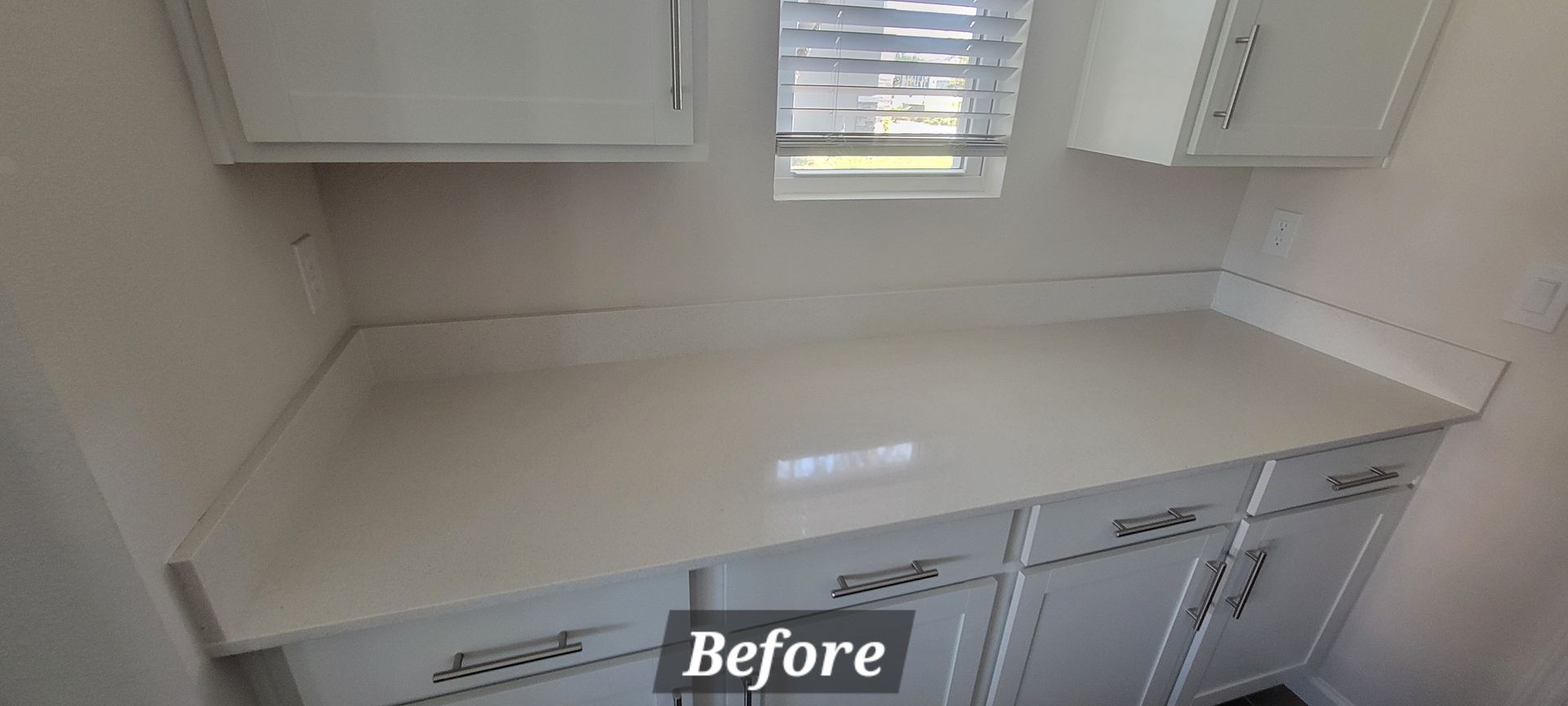A before picture of a kitchen with white cabinets and counter tops.