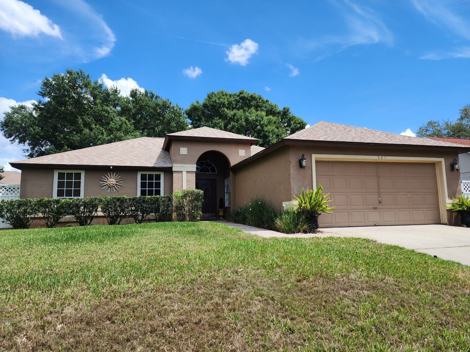 A house with a large garage and a lush green lawn in front of it.