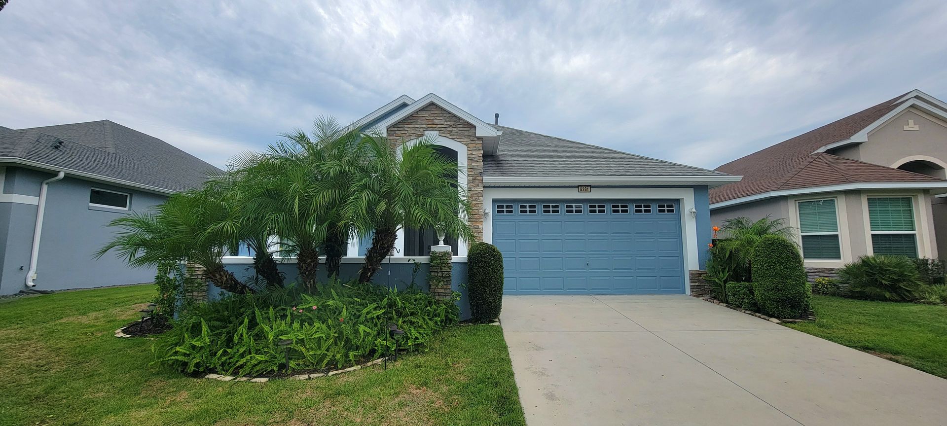 The front of a house with a blue garage door and a driveway.
