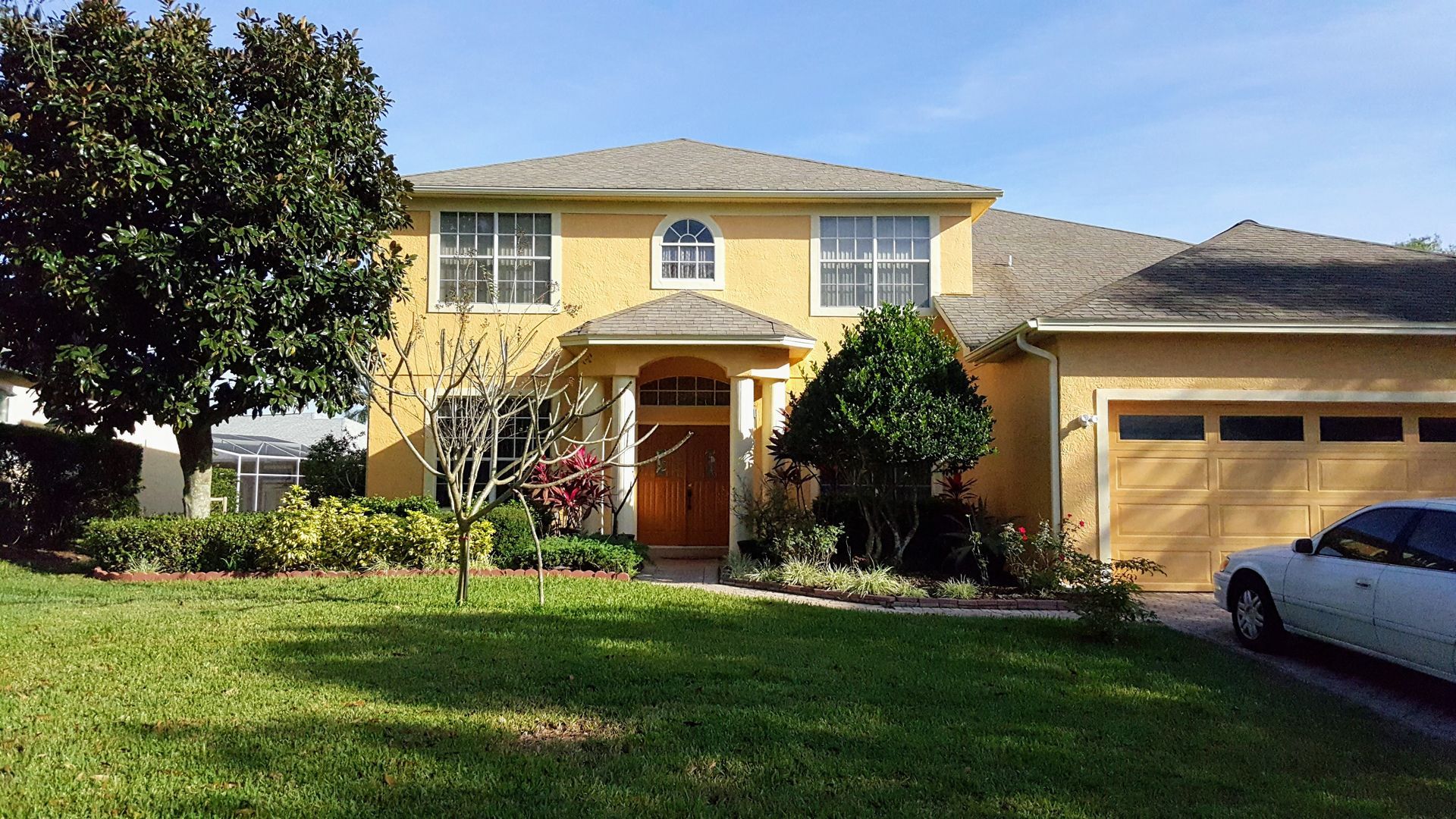 A yellow house with a white car parked in front of it