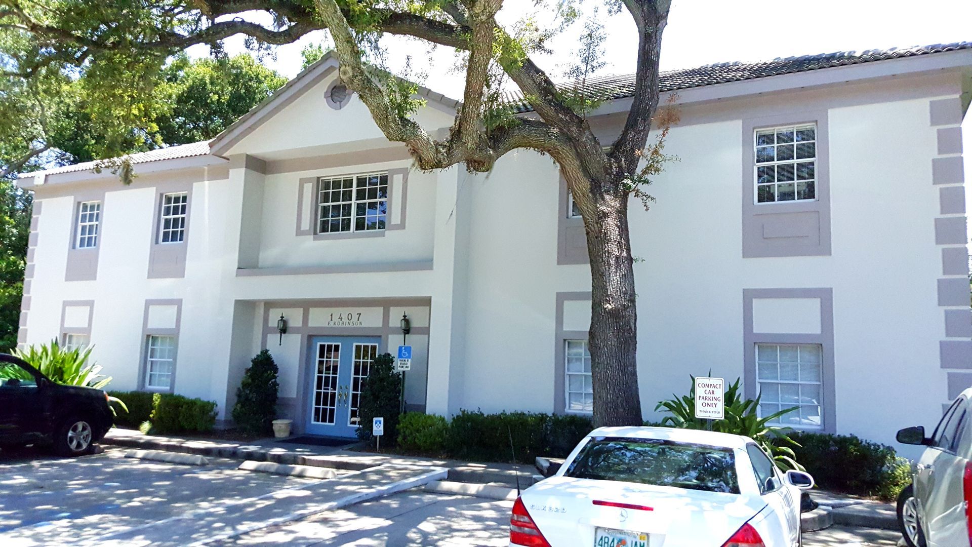A white car is parked in front of a white building