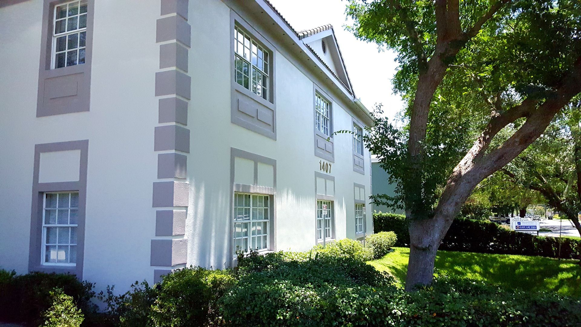 A white building with a tree in front of it