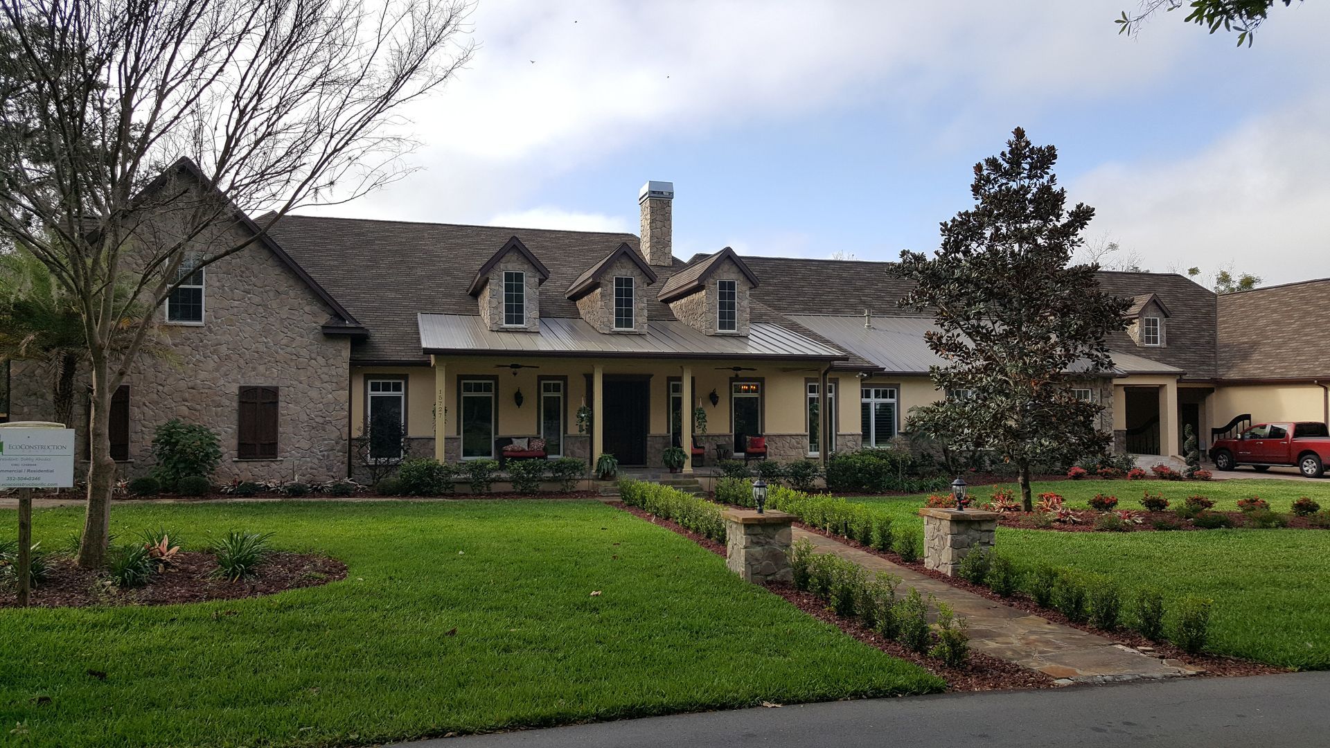 A large house with a large lawn and a red car parked in front of it