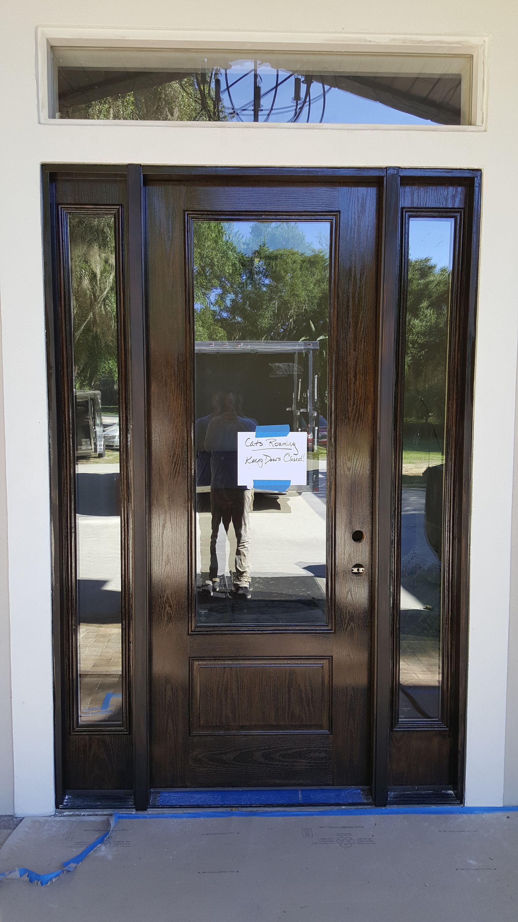 A large wooden door with a lot of glass is being painted.