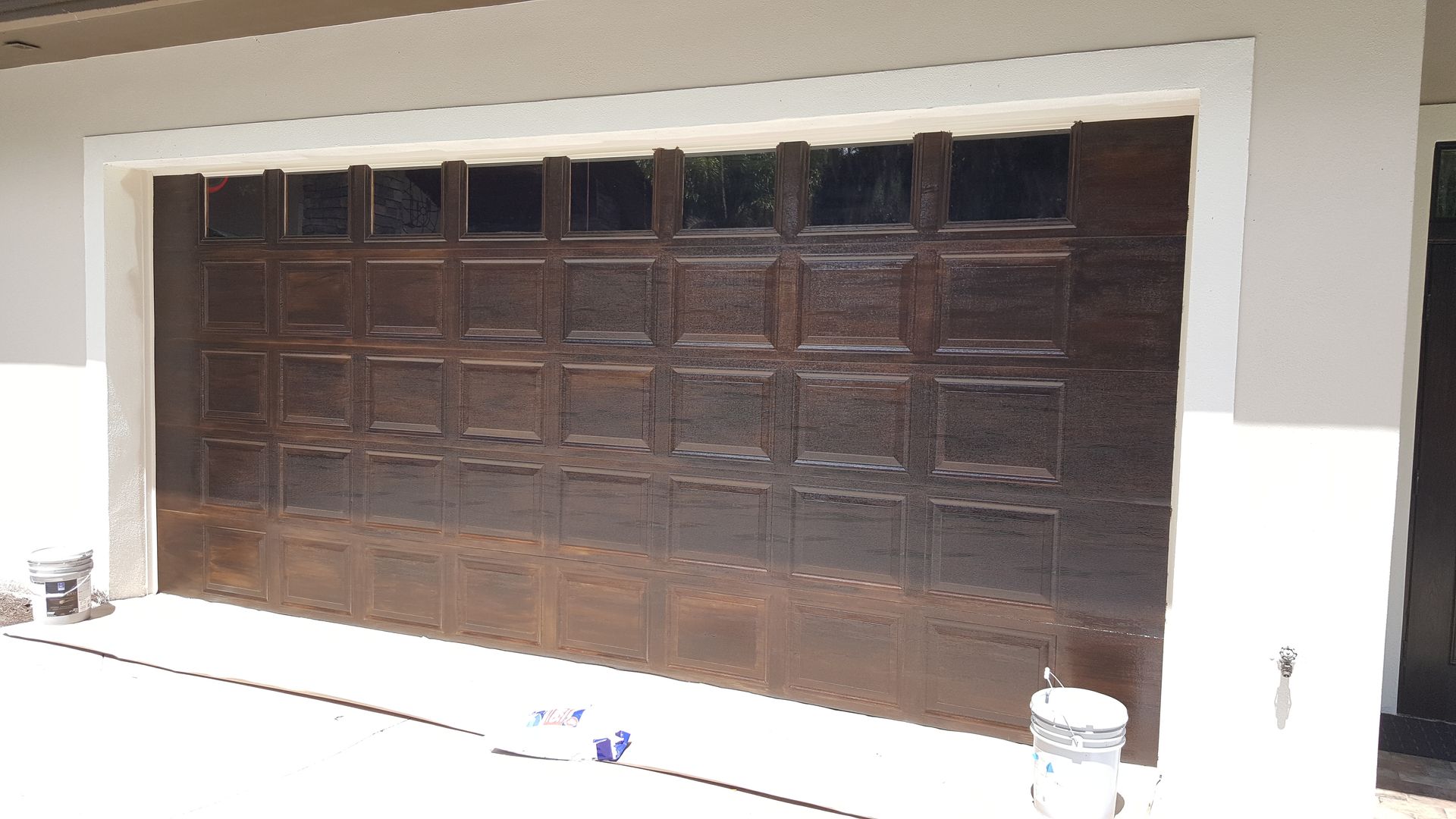 A garage door is being painted brown and white.