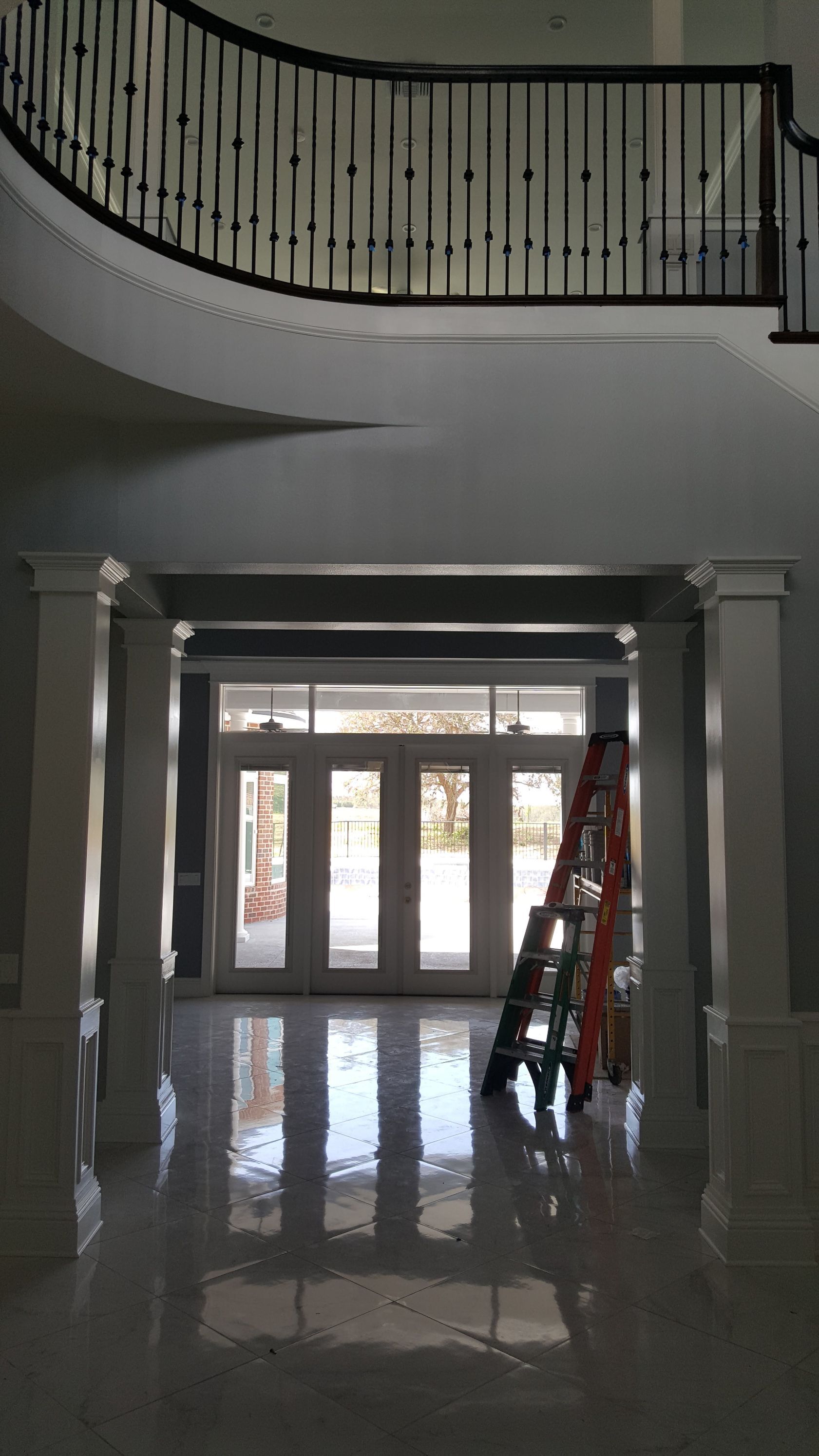 A ladder is sitting in the middle of a hallway next to a staircase.
