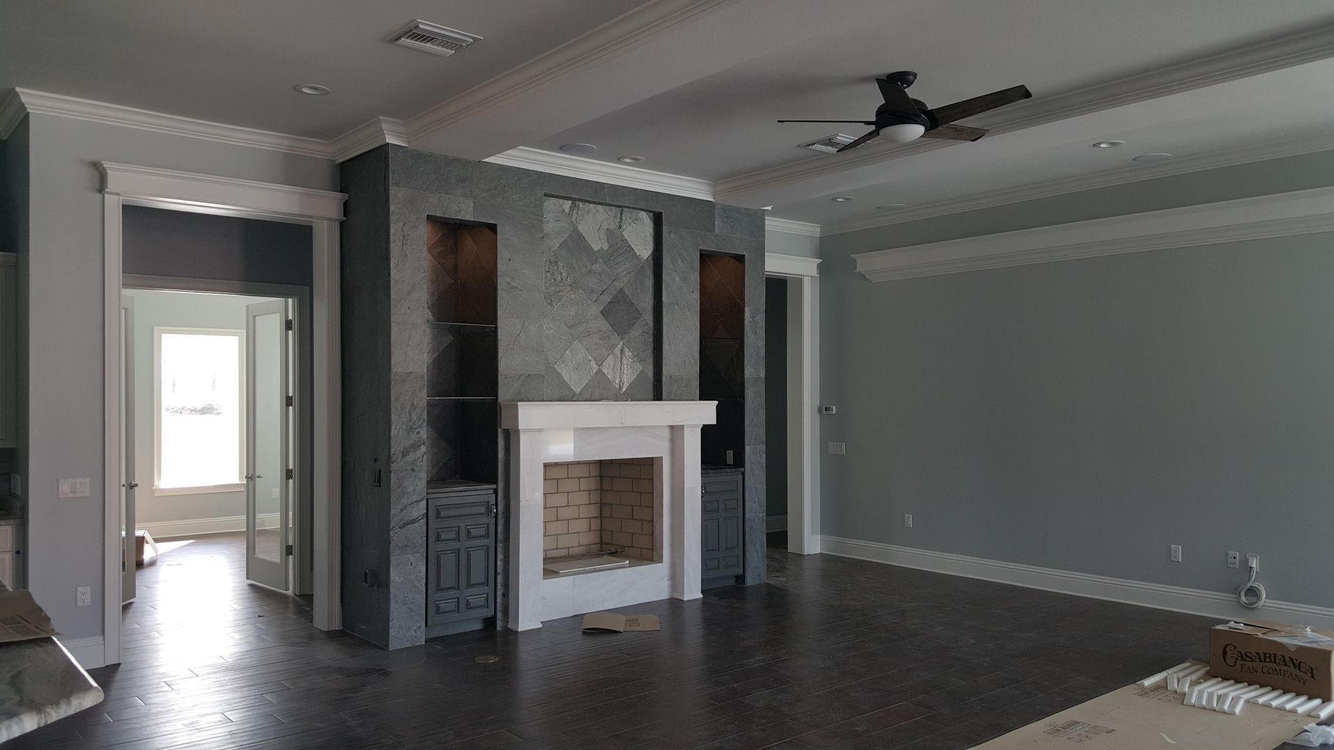 An empty living room with a fireplace and a ceiling fan.