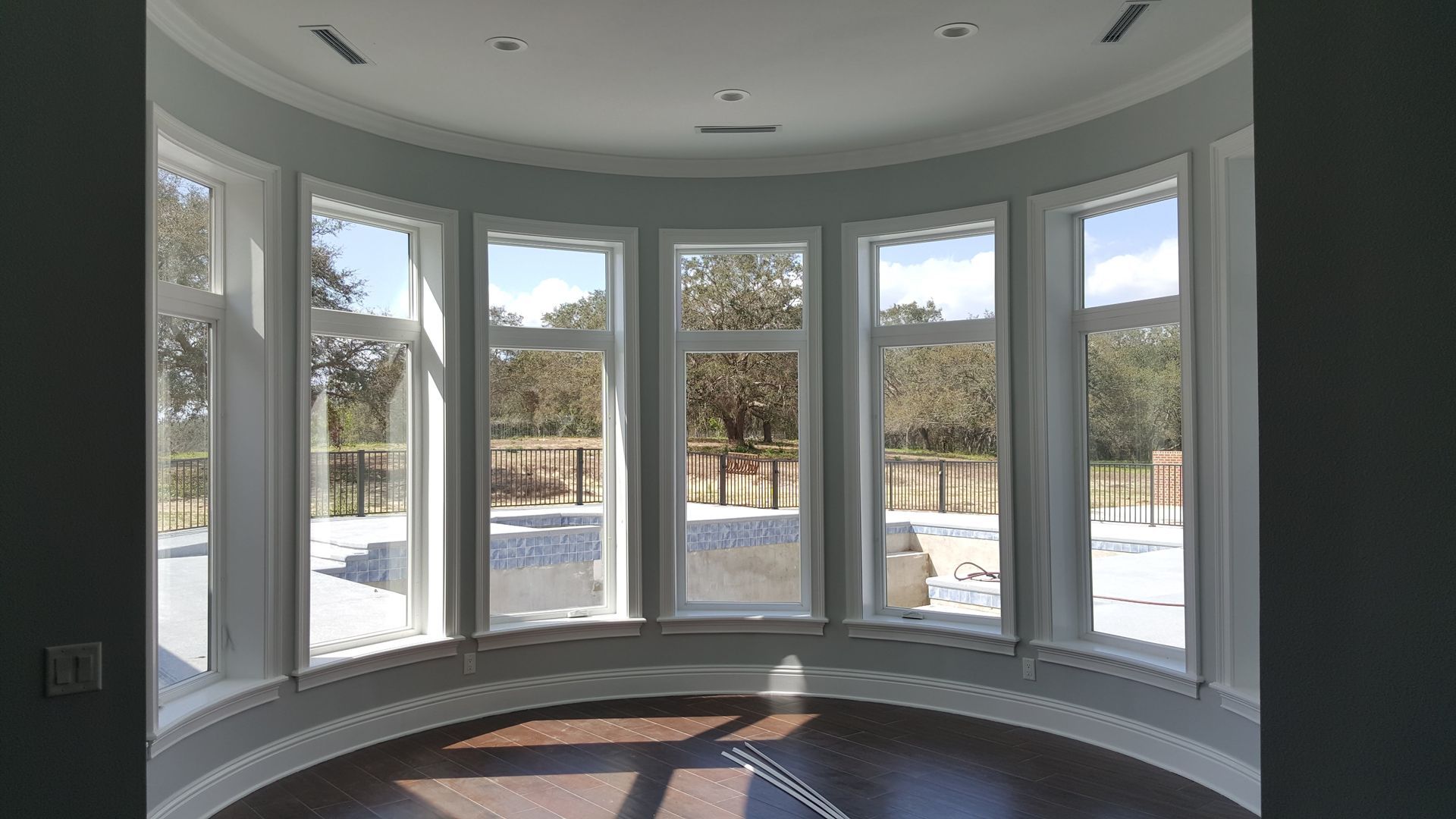 A room with a lot of windows and a pool in the background
