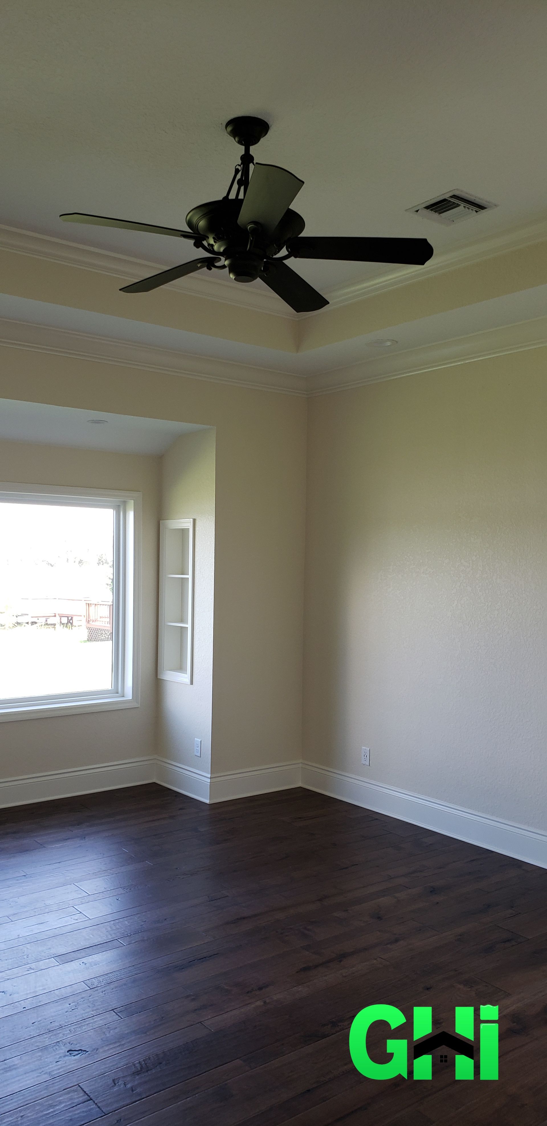 An empty room with a ceiling fan and a window.