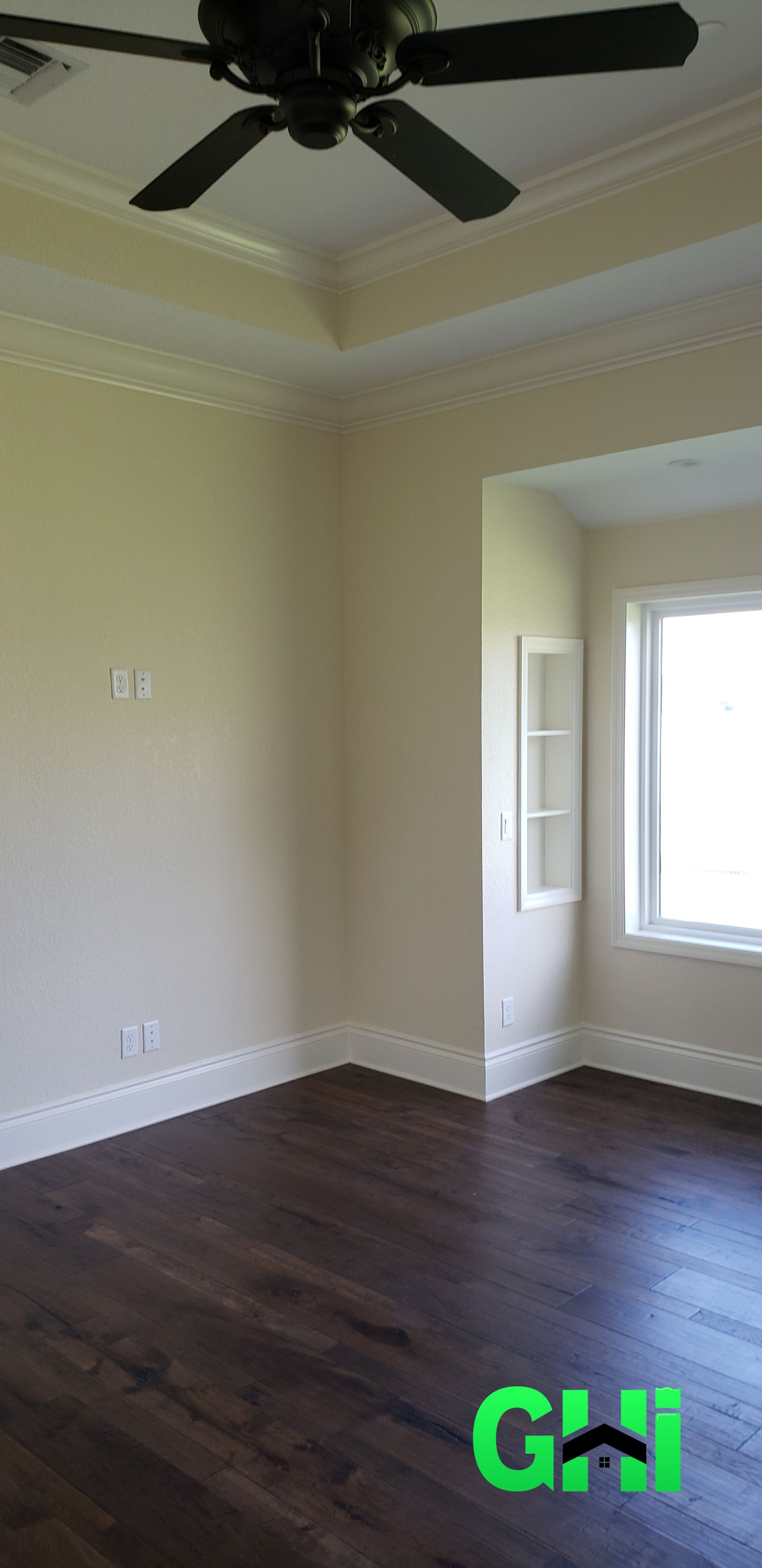 An empty room with a ceiling fan and a window.