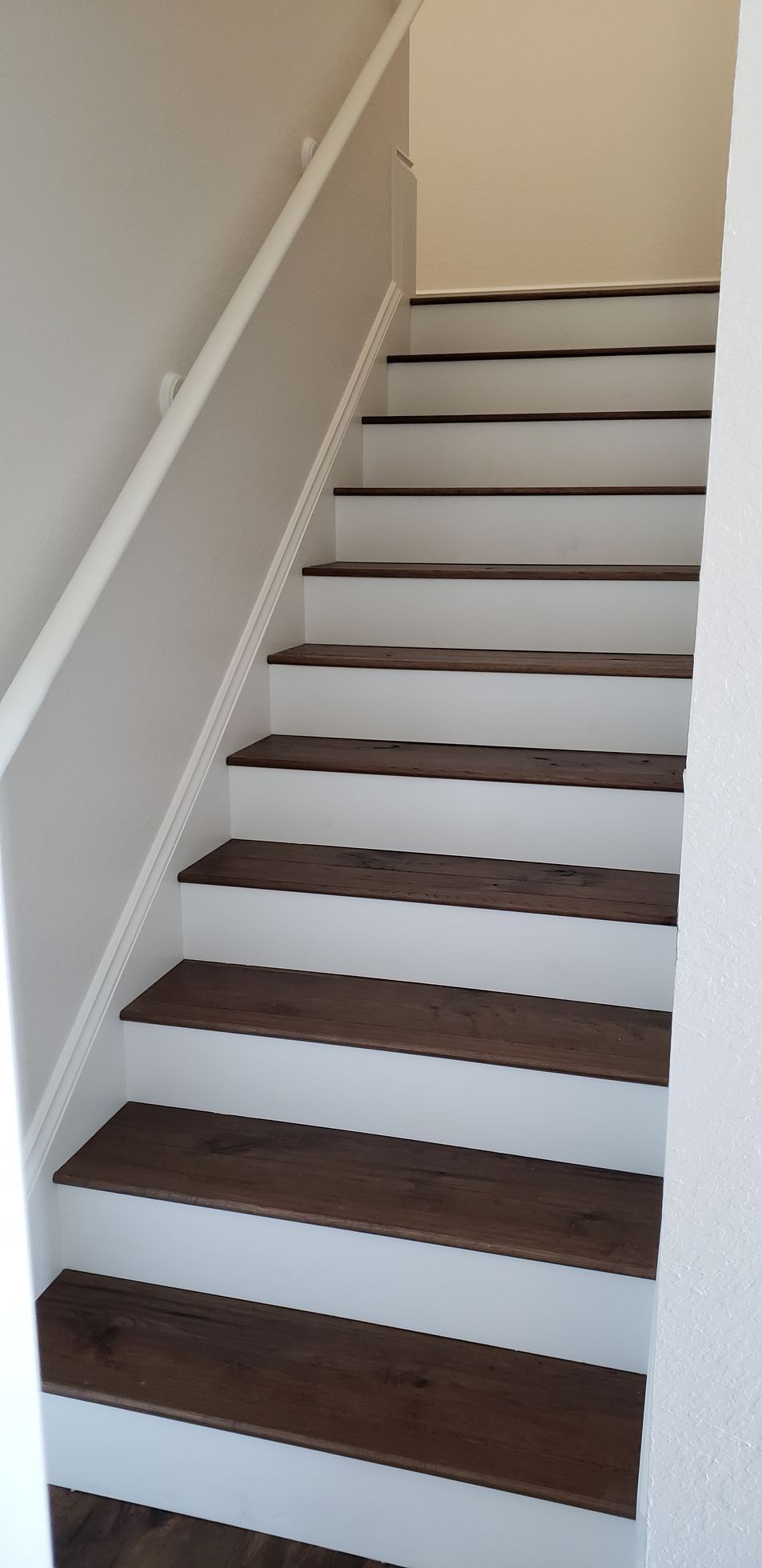 A set of wooden stairs with white steps and a white railing.