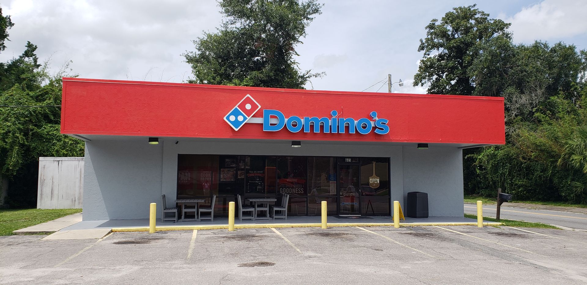 A domino 's pizza restaurant with a red roof and a parking lot in front of it.