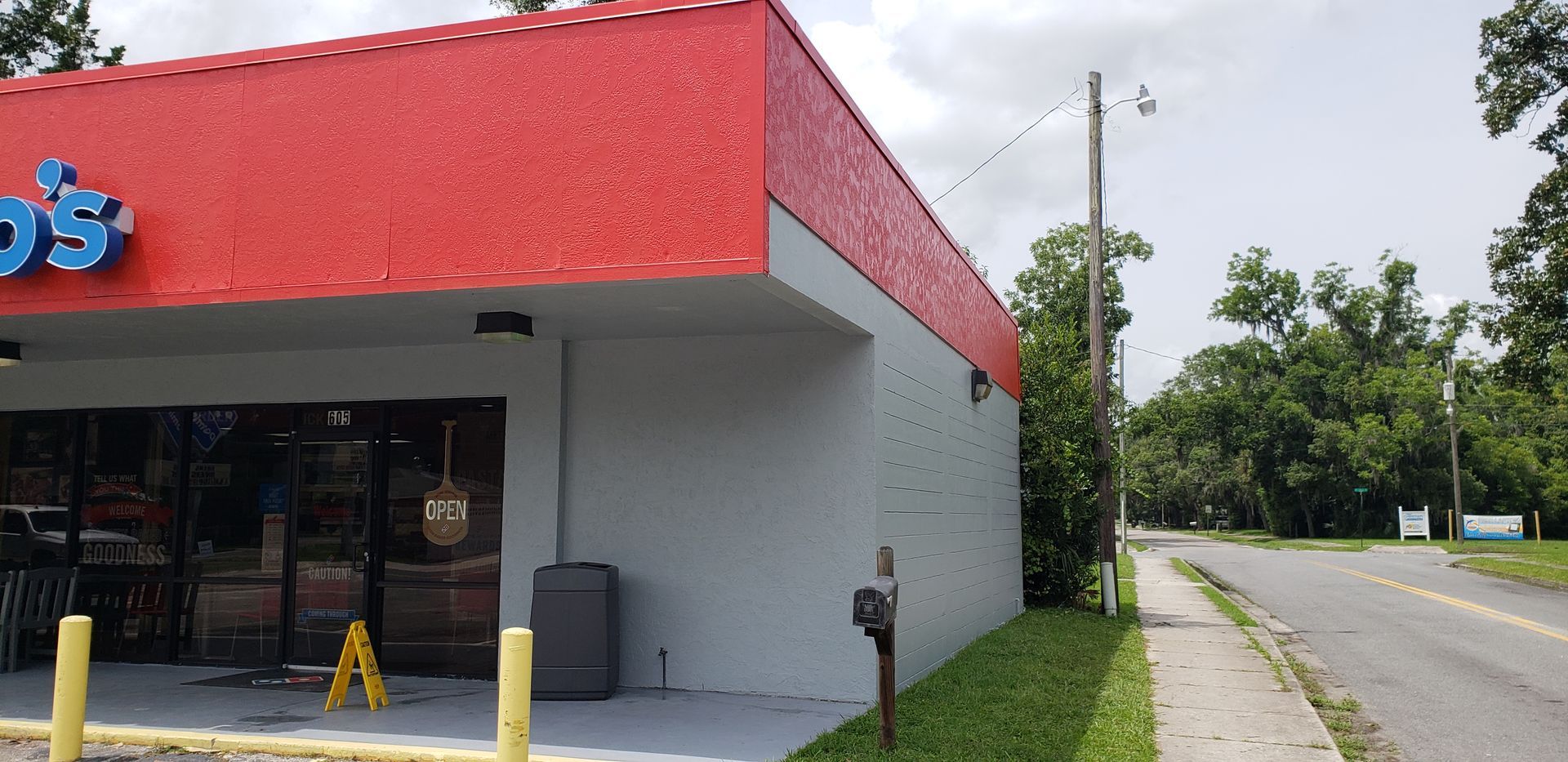 A white building with a red roof is next to a road.
