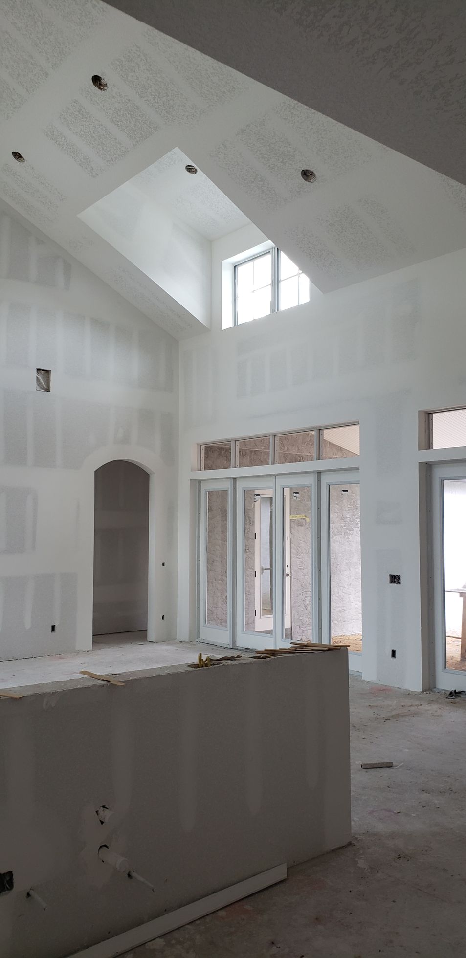 A large empty room with a vaulted ceiling and sliding glass doors.