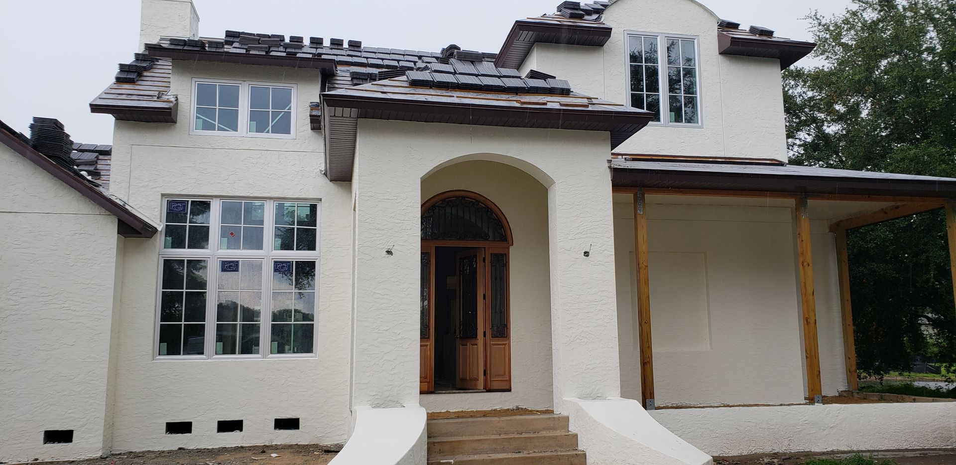 A white house with a porch and stairs in front of it.