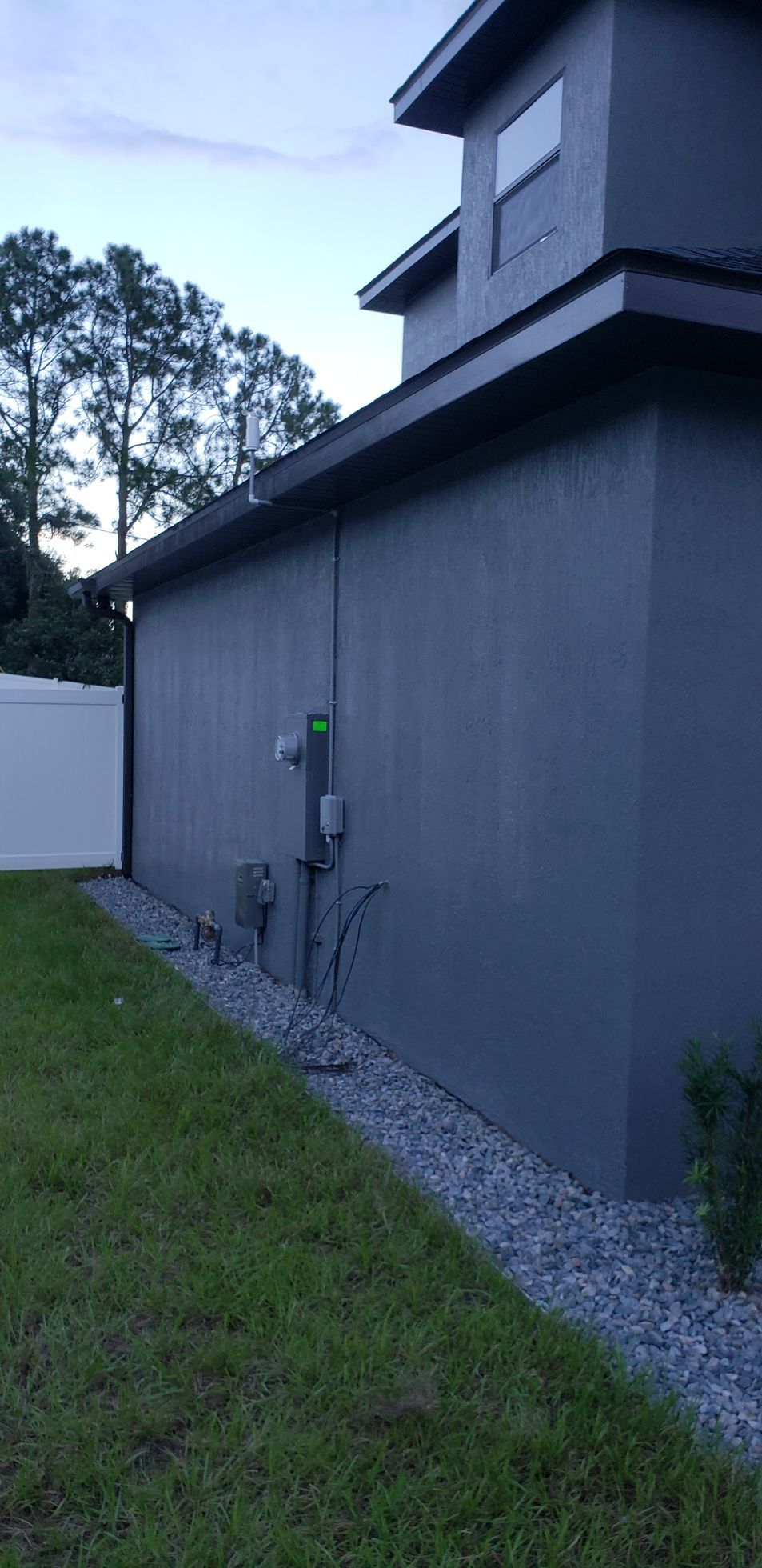 A gray house with a white fence in the backyard.