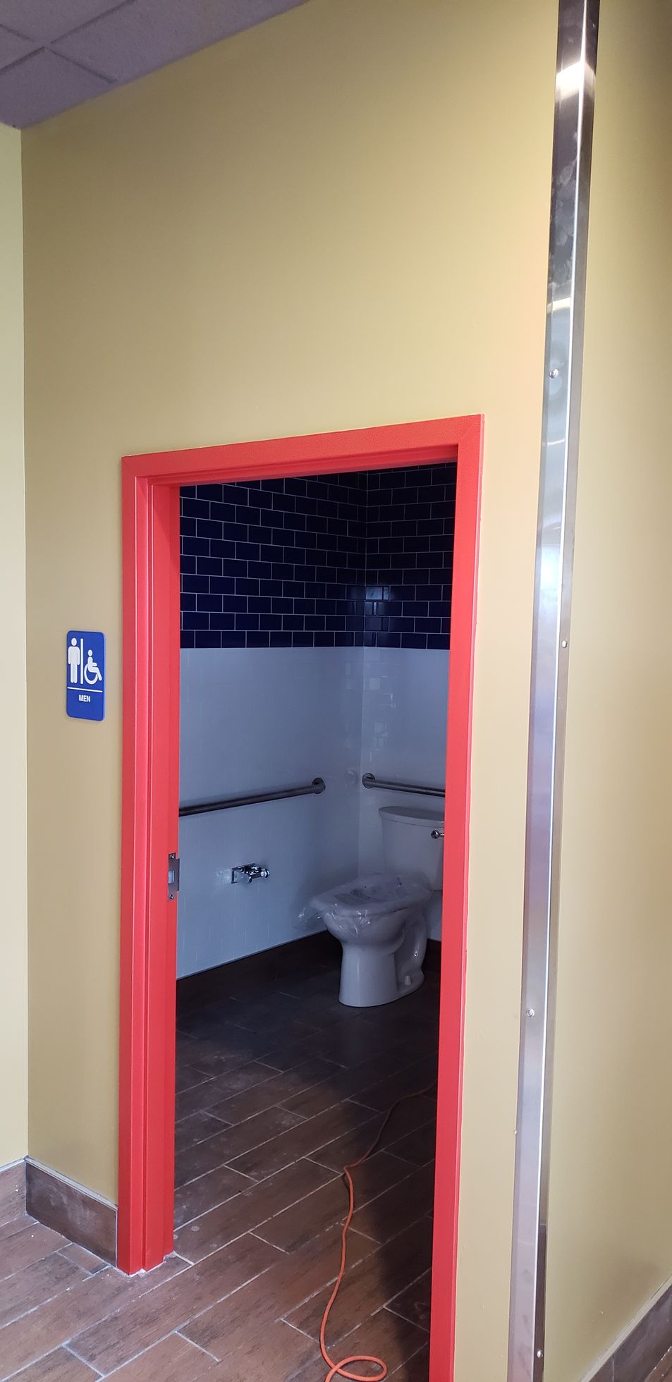 A bathroom with a red door and a toilet.