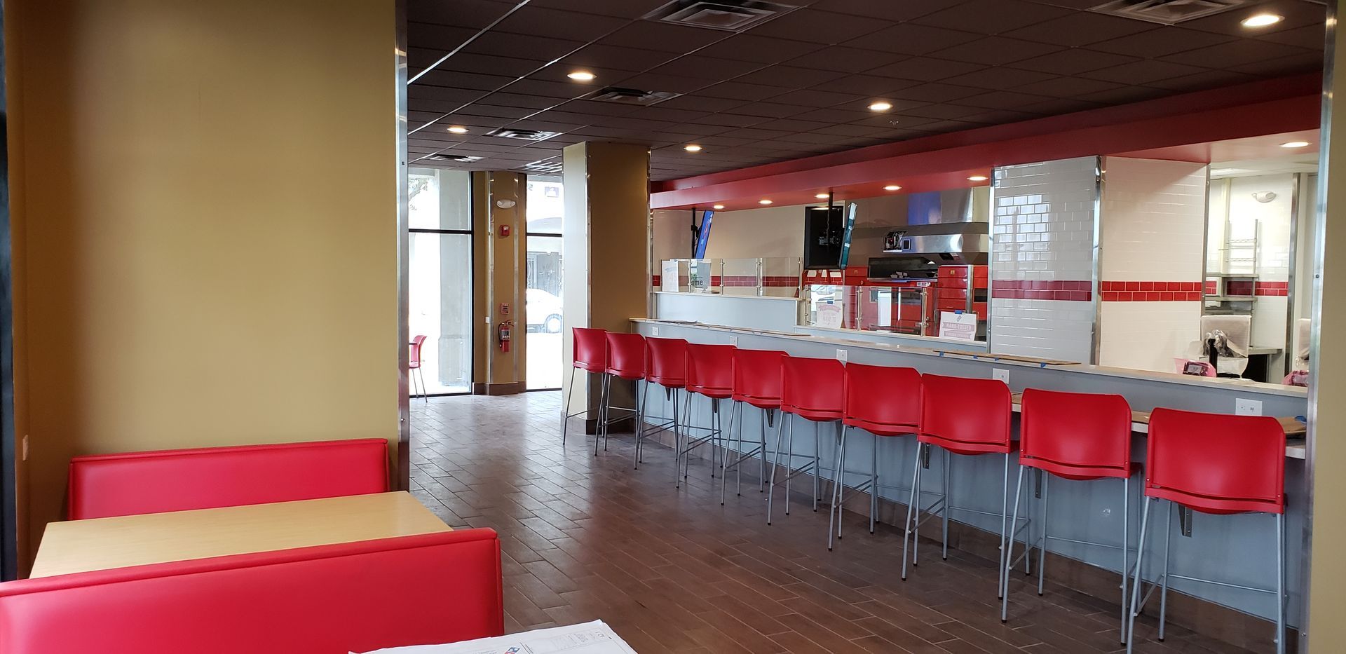A restaurant with red tables and chairs and a long counter.