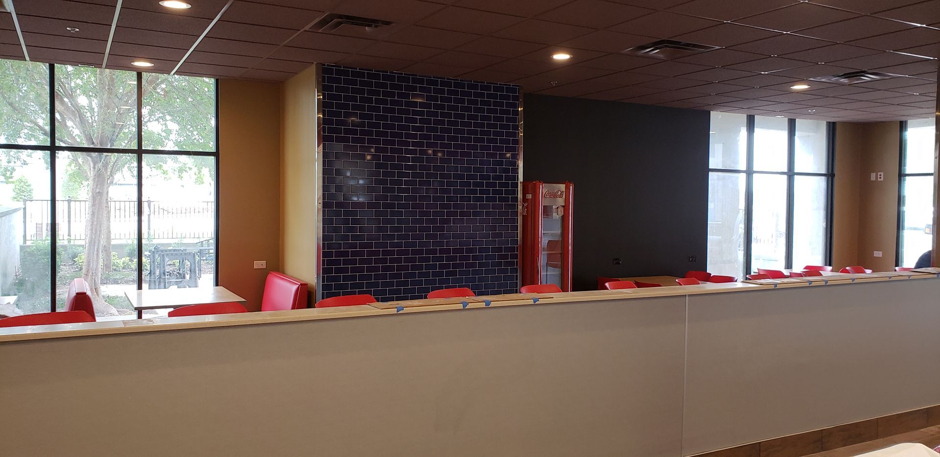 There is a long counter in the middle of a room with a lot of windows.