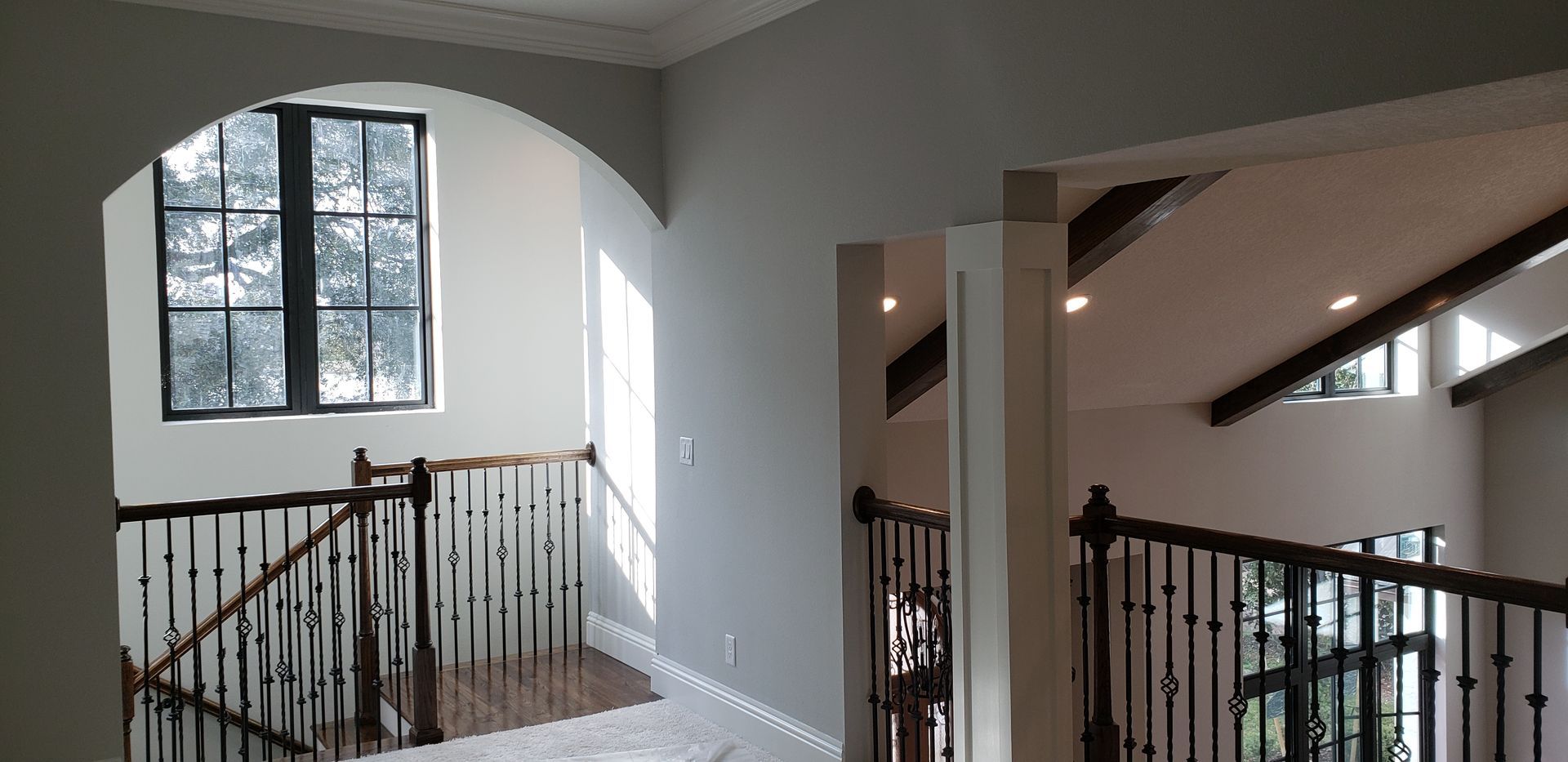 A staircase in a house with a wrought iron railing and a window.