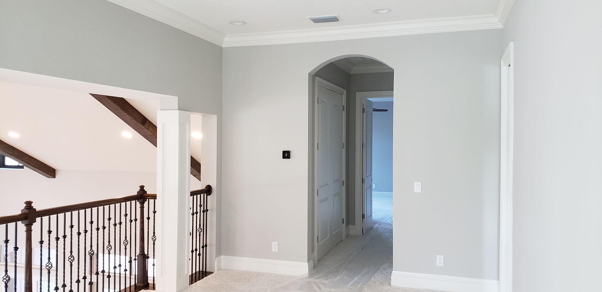 An empty hallway in a house with a staircase and a railing.