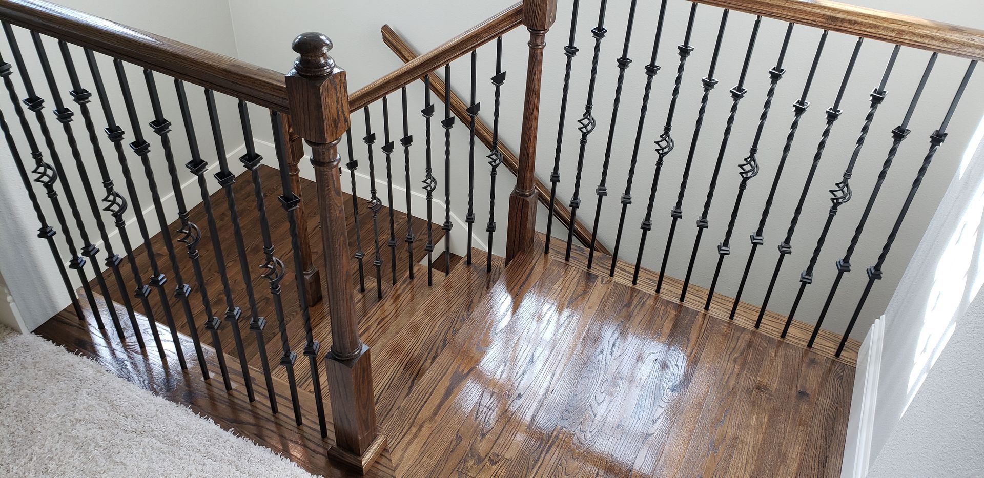 A wooden staircase with a wrought iron railing in a house.