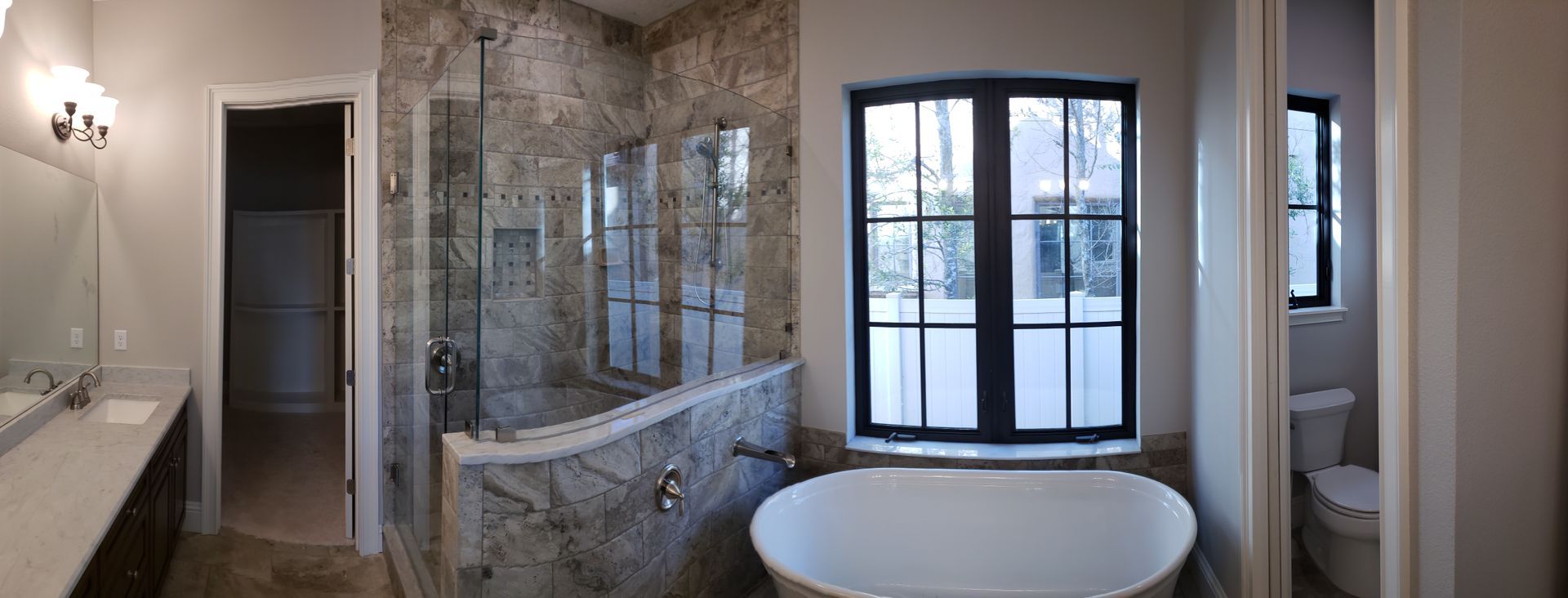 A bathroom with a tub , sink , toilet and window.