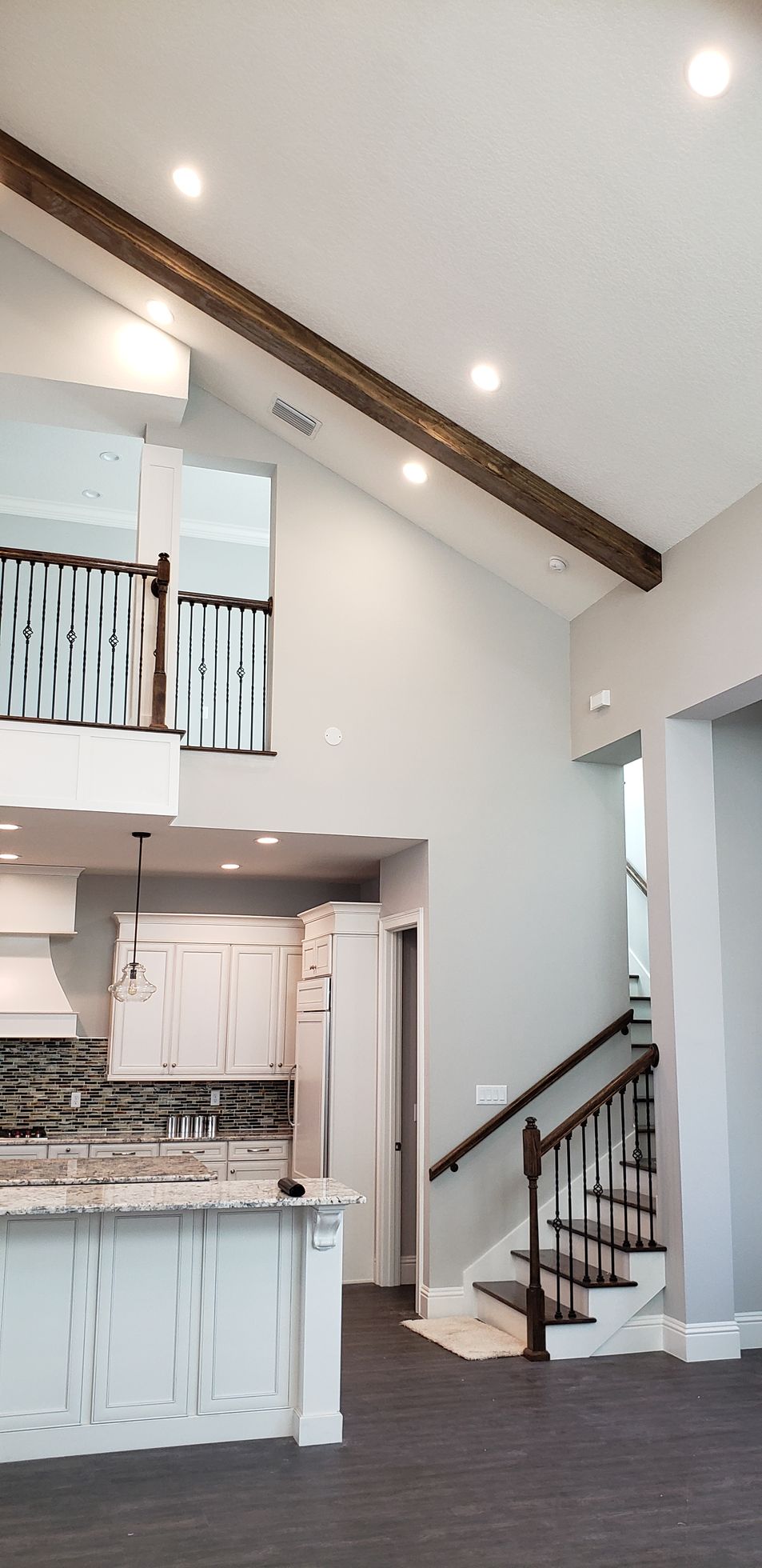 A kitchen with a vaulted ceiling and stairs leading up to the second floor.