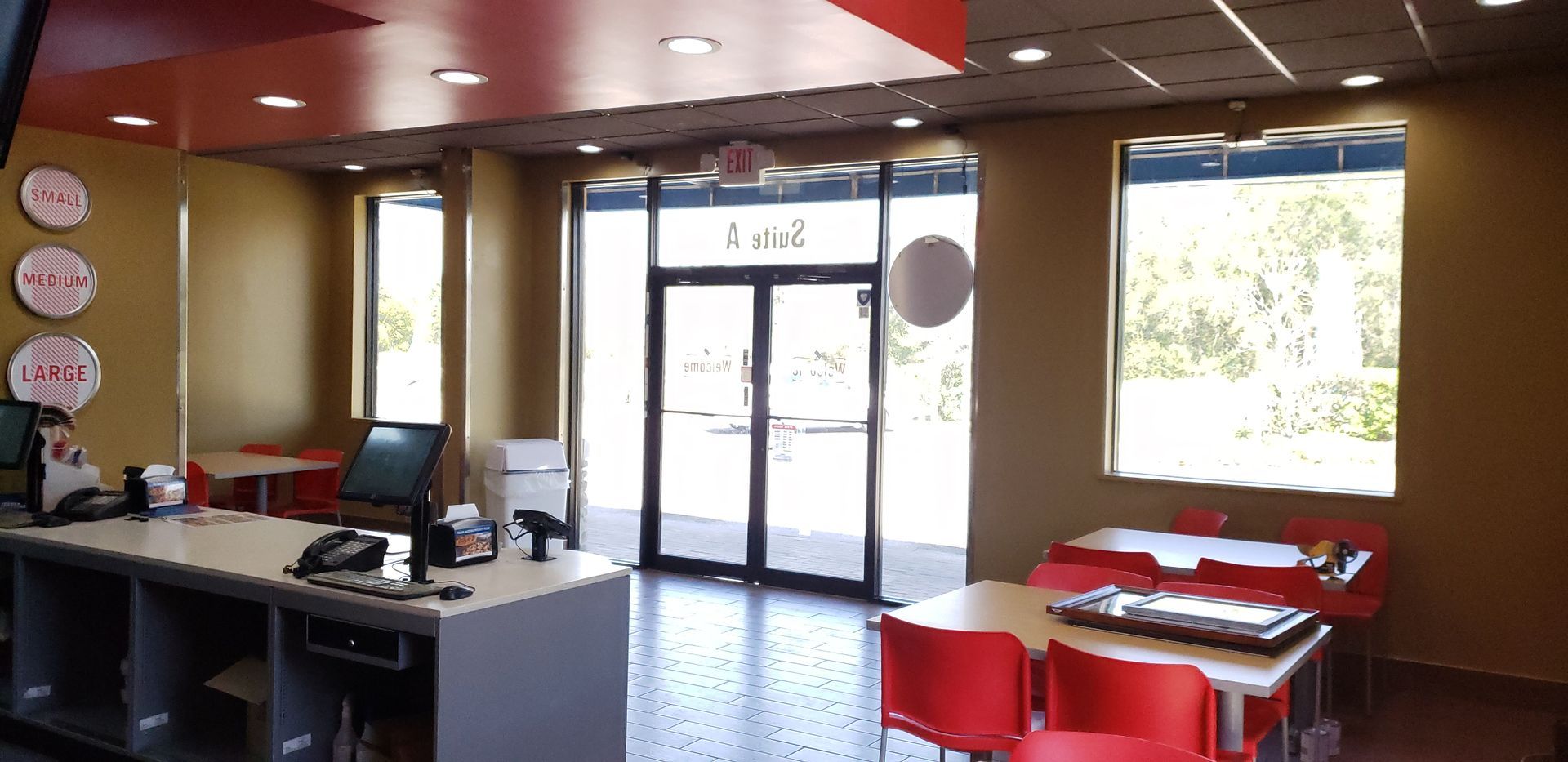 The inside of a restaurant with red chairs and tables